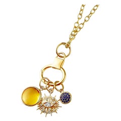 Collana Syna in oro giallo con tre charms per il malocchio, pietre preziose e diamanti