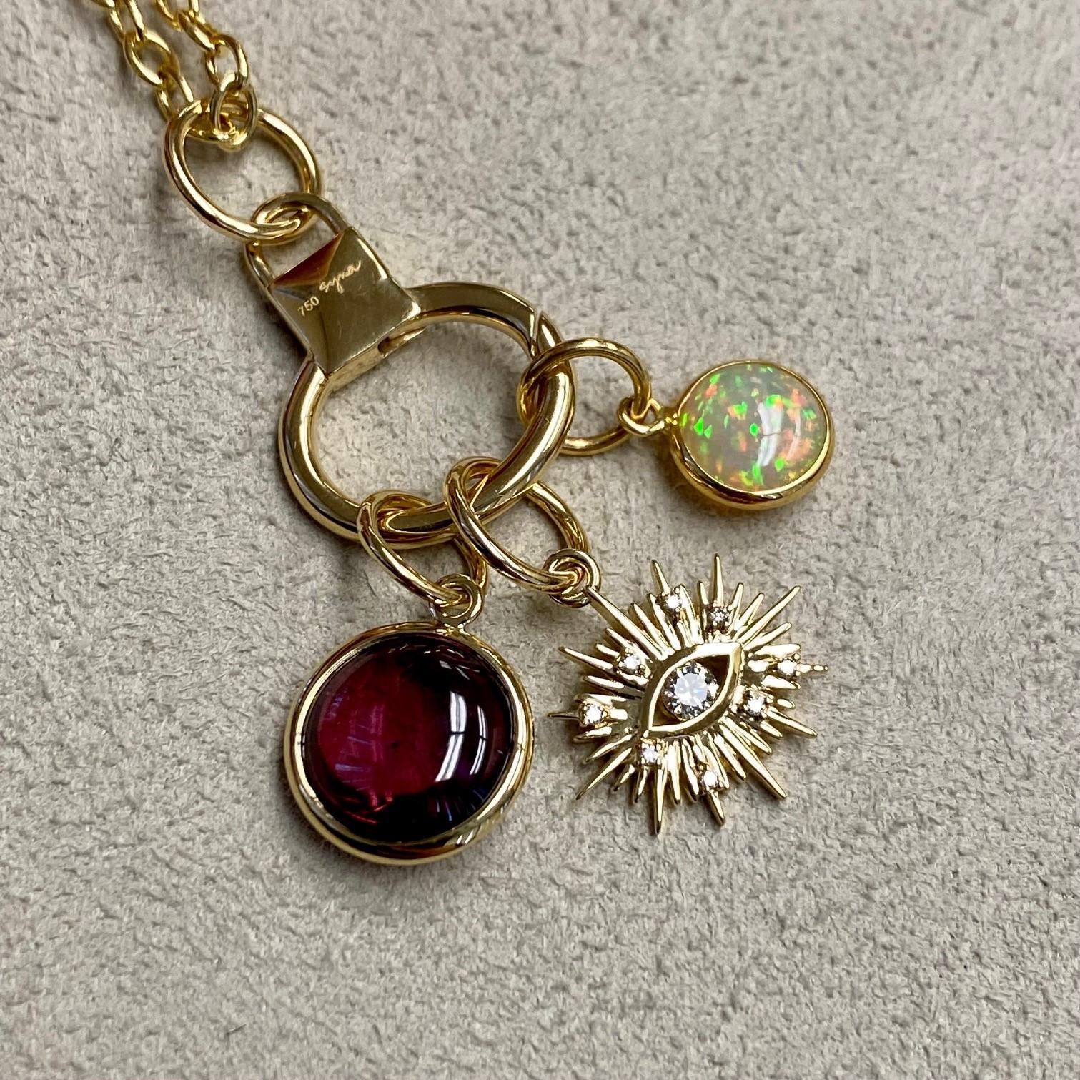 Created in 18 karat yellow gold
Rhodolite garnet 3.50 carats approx.
Opal 0.80 carat approx.
Diamonds 0.10 carat approx.
Limited edition
Chain sold separately

Hand-crafted from 18 karat yellow gold, this limited-edition Three charms features a