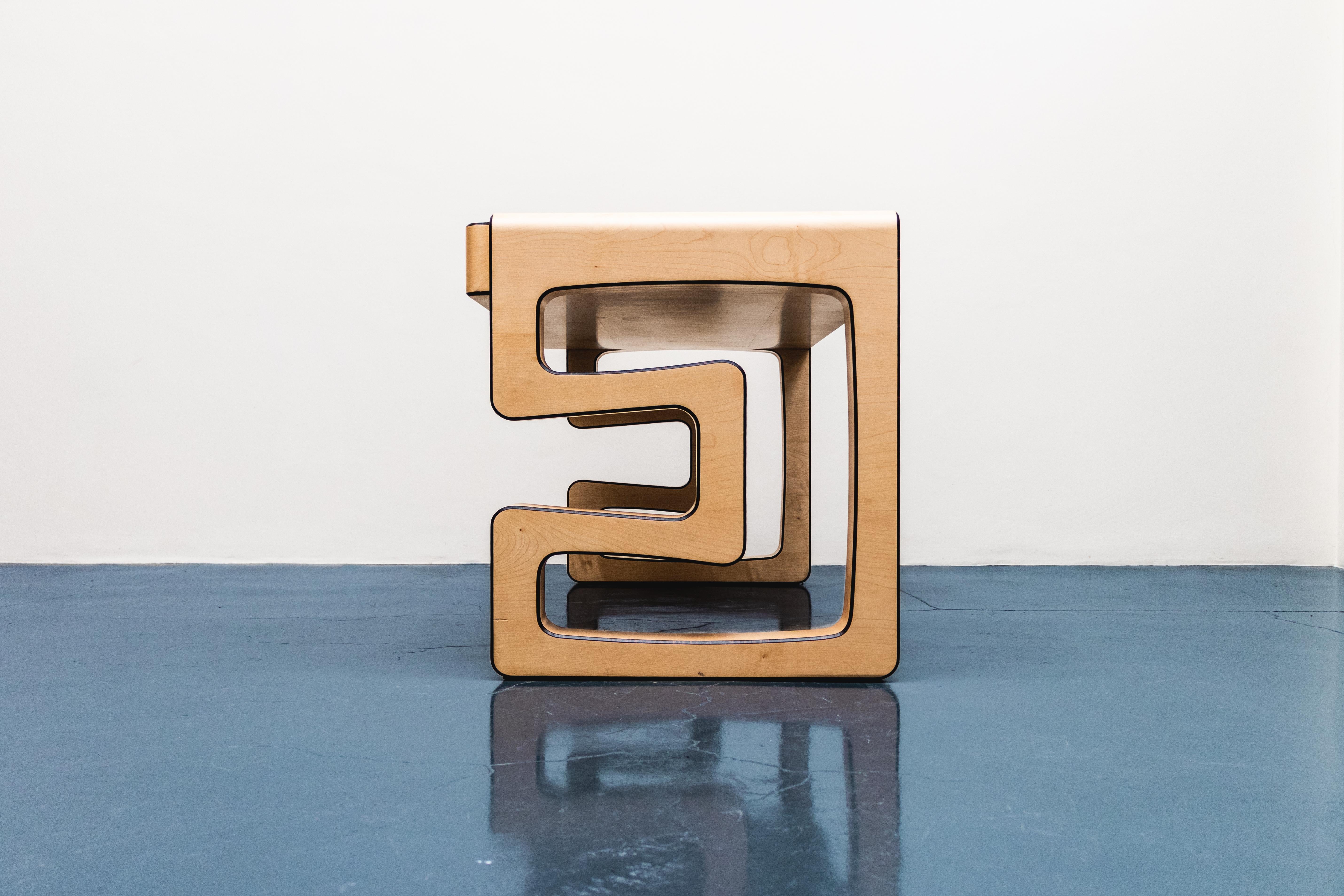 The eye-catching Synchronicity desk stands out of all common tables. The extraordinary features of this magnificent handmade desk crafted of maple wood are the two unique, hollow C-shaped legs that support a stately top. Two drawers subtly emerge to