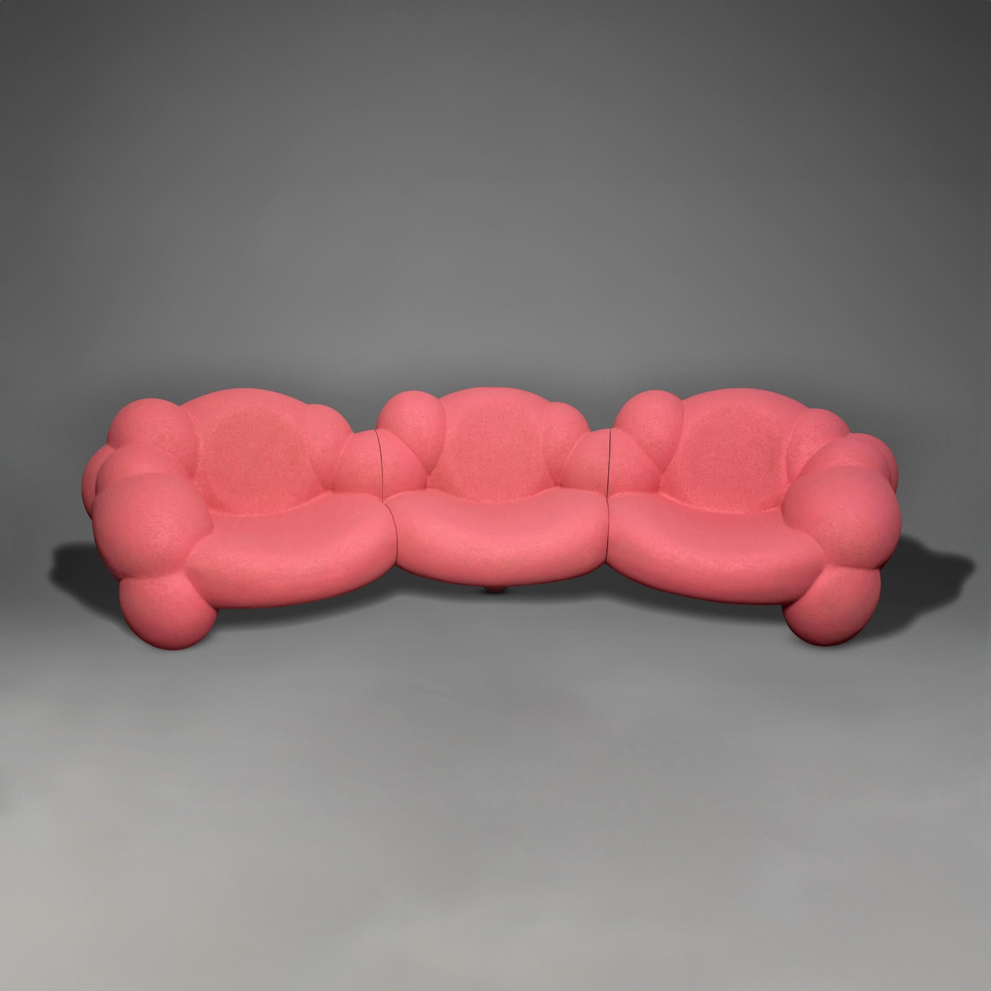 Si tratta di un divano a tre posti composto da tre sezioni di sedute, le cui curve voluminose ed espansive sono un palloncino, come se volesse fluttuare lontano da terra. Ci sono due divani rosa che formano un cerchio intorno al tavolino