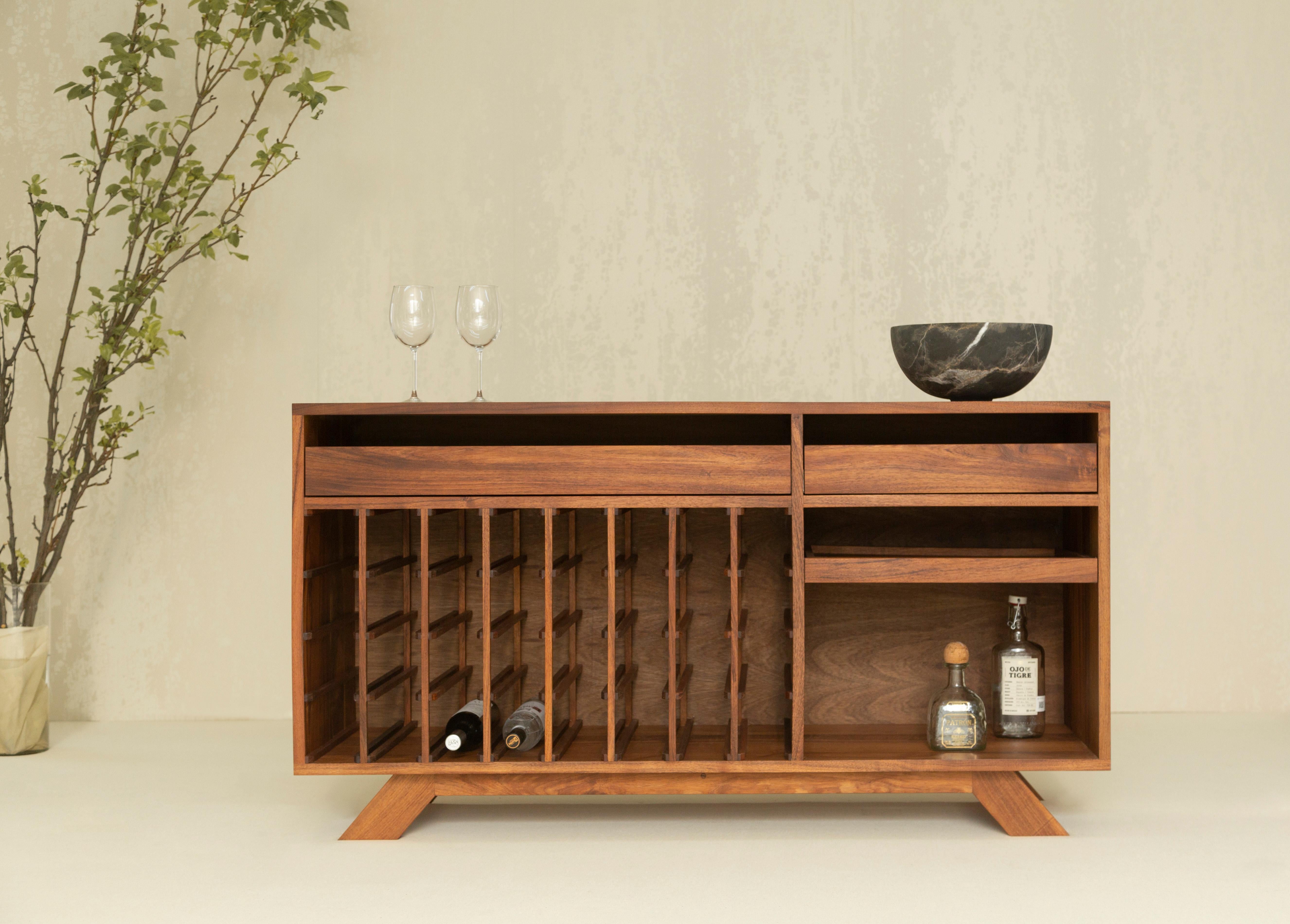 The Syrah wine cabinet is the perfect piece to place inside a dining room. It serves the purpose of storing a wine collection and has additional drawer space for more bottles or other items. It is made with a Mexican hardwood called Tzalam. It has