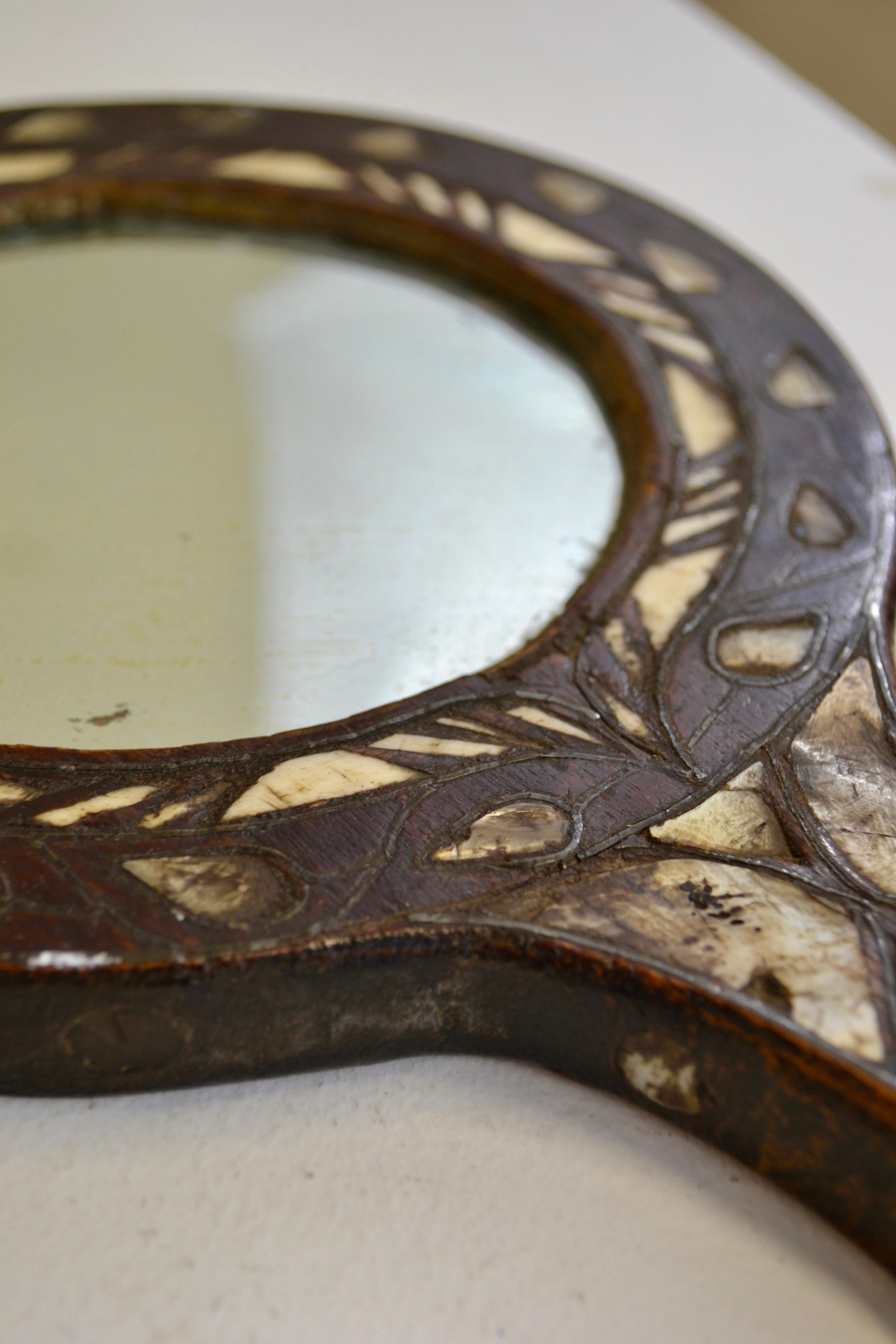 A rare and evocative 19th-century Syrian hand mirror, masterfully crafted from carved wood and delicately inlaid with shimmering mother-of-pearl. This exquisite piece reflects the rich artistic heritage and meticulous craftsmanship of the Levant,