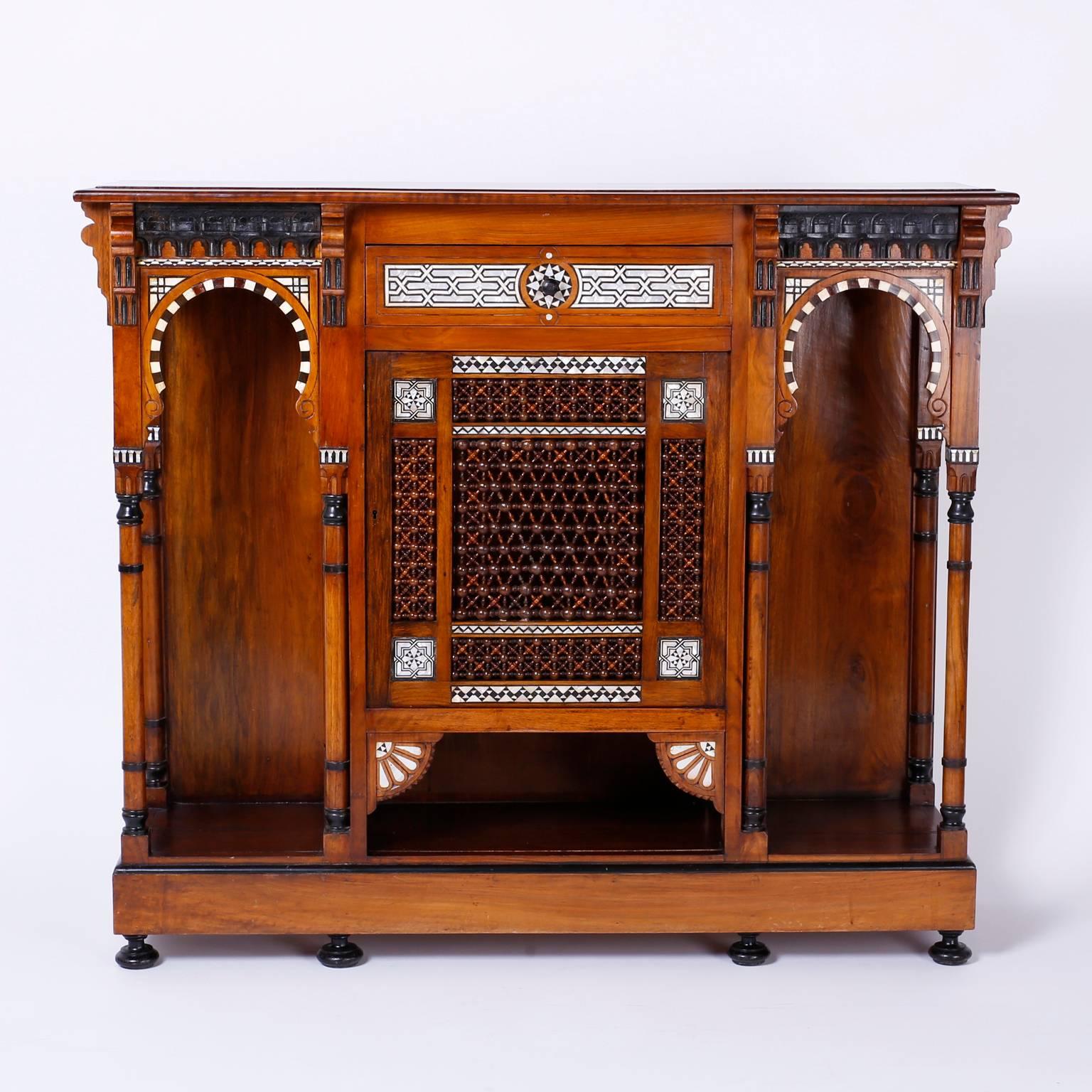 Fine antique Syrian cabinet or server crafted with walnut and
decorated with inlaid mother of prattle and bone. Having two Moorish
arches and a centre door with stick and ball panels and a single
drawer above. This inspired structure sits on a