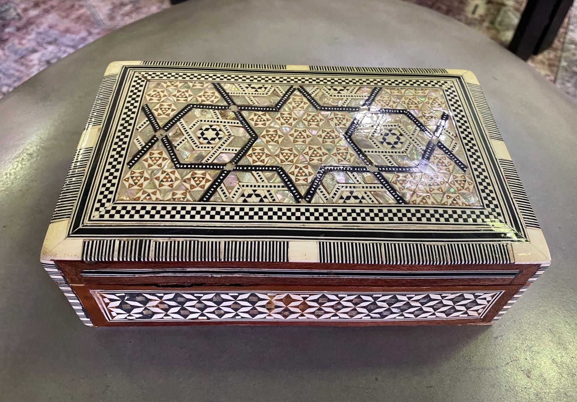 Stunning mosaic design and gorgeous craftsmanship. The box is made of various woods and mother-of-pearl inlays. A genuine work of art. 

Would clearly stand out in any setting. Unique and alluring overall. 

Dimensions: 8