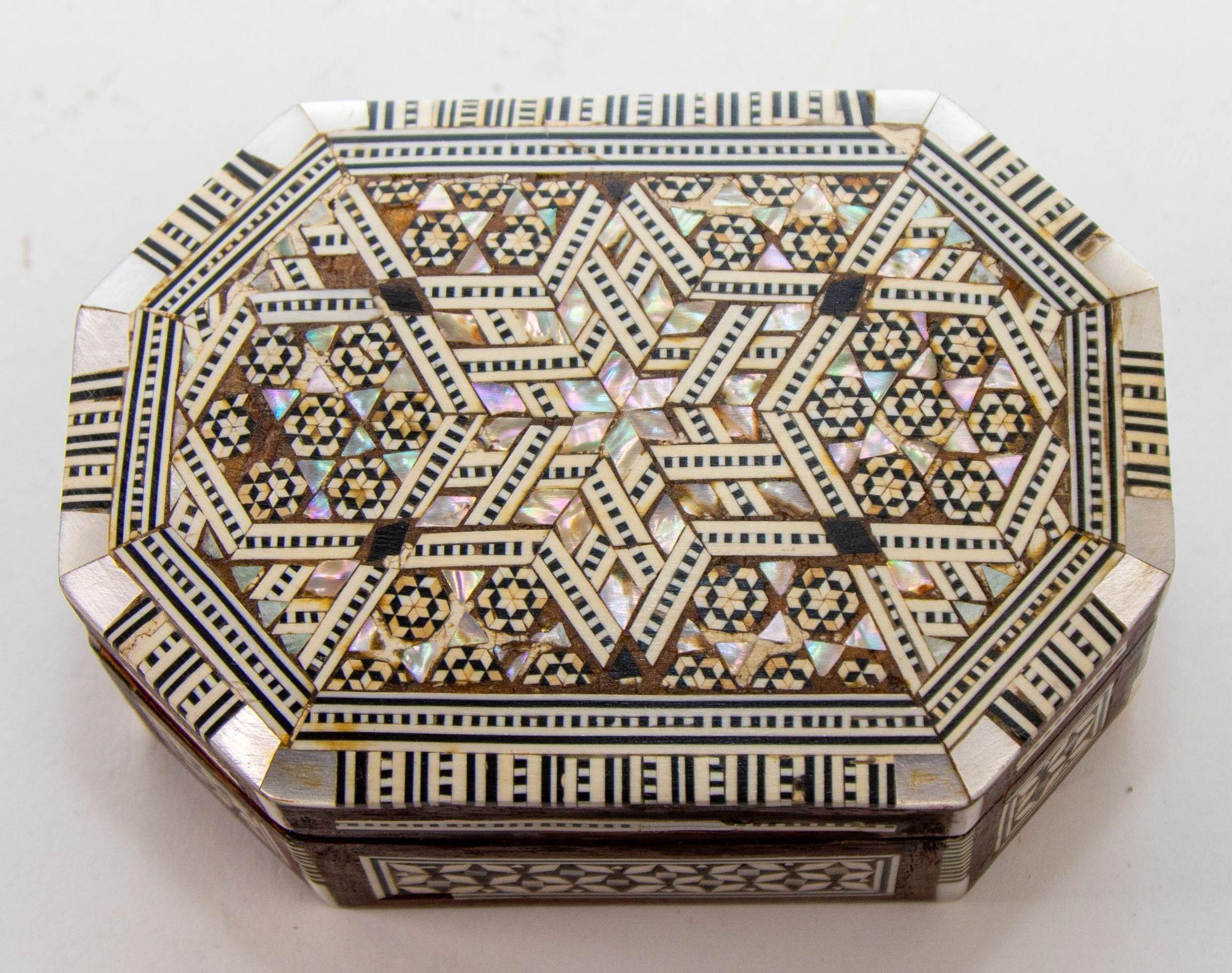 Syrian Moorish Middle Eastern Mother of Pearl Inlaid Mosaic Jewelry Box.
1950s Exquisite handcrafted Middle Eastern mosaic marquetry inlaid walnut wood trinket box.
Small octagonal box intricately decorated with Moorish motif designs which have been
