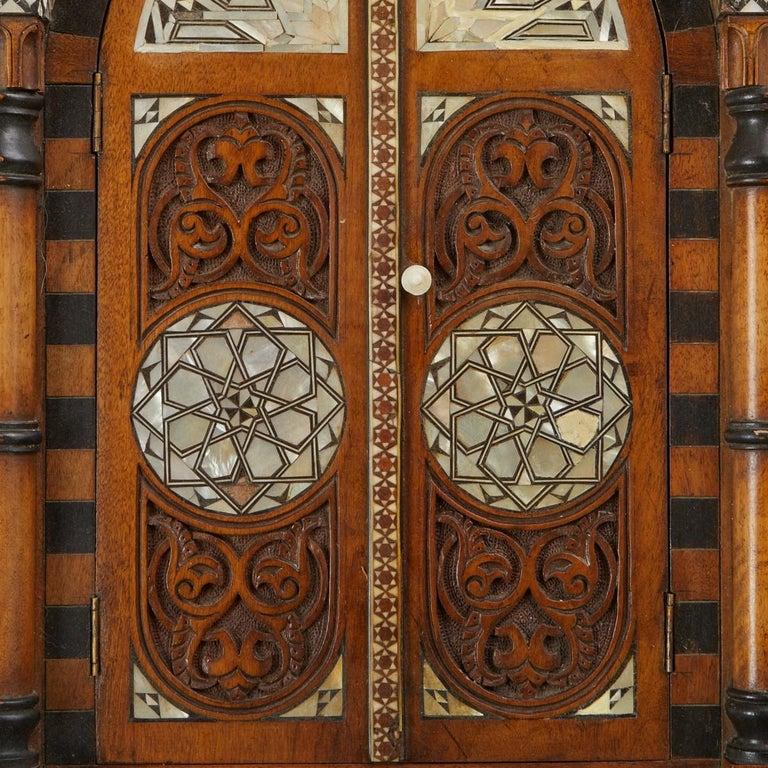 Armoire murale du 19e siècle, de forme architecturale, avec marqueterie complexe en noyer, nacre de bois contrastée et bois ébonisé. L'étage supérieur est constitué d'une galerie à frettes finement percée et de supports à consoles de chaque côté. Le