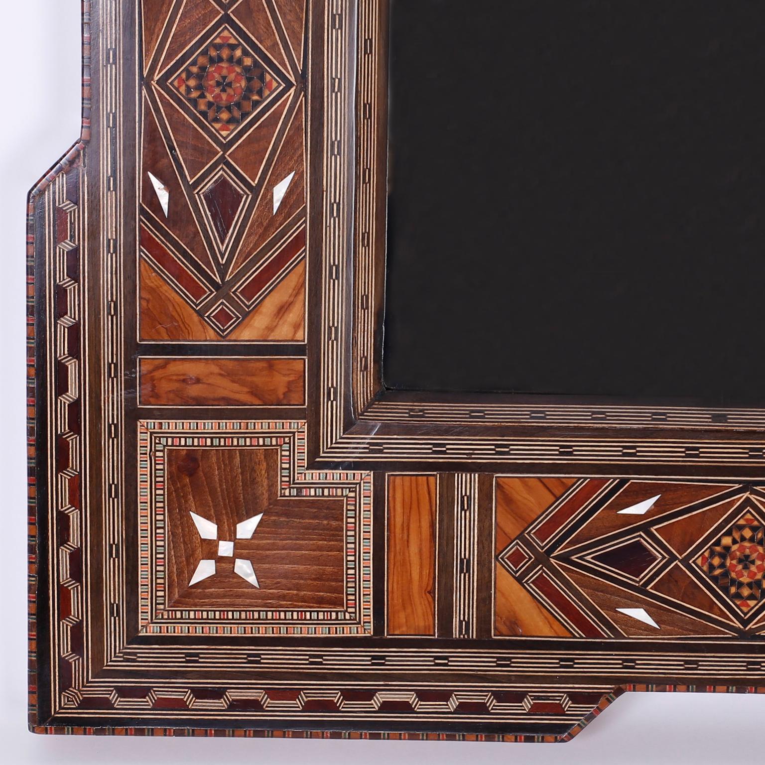 Inspired Syrian mirror and frame ambitiously inlaid with walnut, mahogany, ebony bone, dyed wood, marquetry, and mother-of-pearl in ubiquitous symbolic geometric designs, in the Moorish manner.
