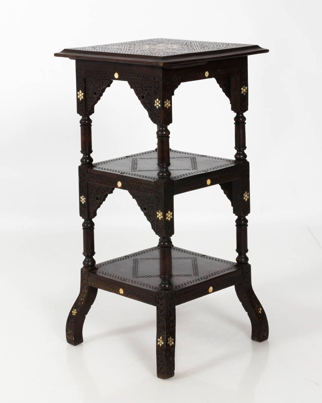 Hand-carved walnut wise table from Syria with geometric mother-of-pearl inlay with three tiers, circa early 20th century. This table also features decorative floral. Carvings throughout with Arabesque arches.