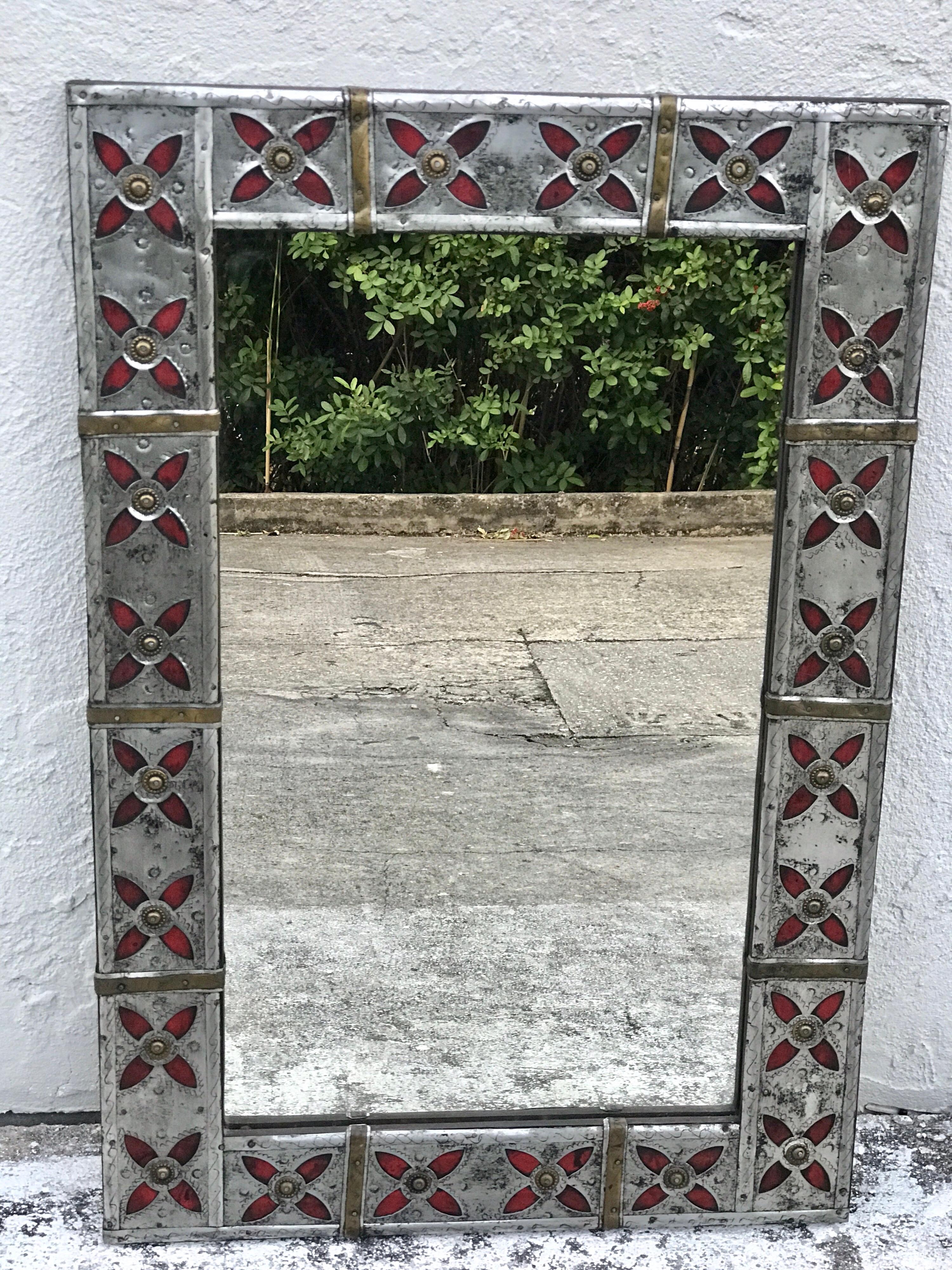 Syrian Pewter, brass and enameled mirror. Of rectangular form with chased pewter and brass frame, with a continuous surround of red enameled 