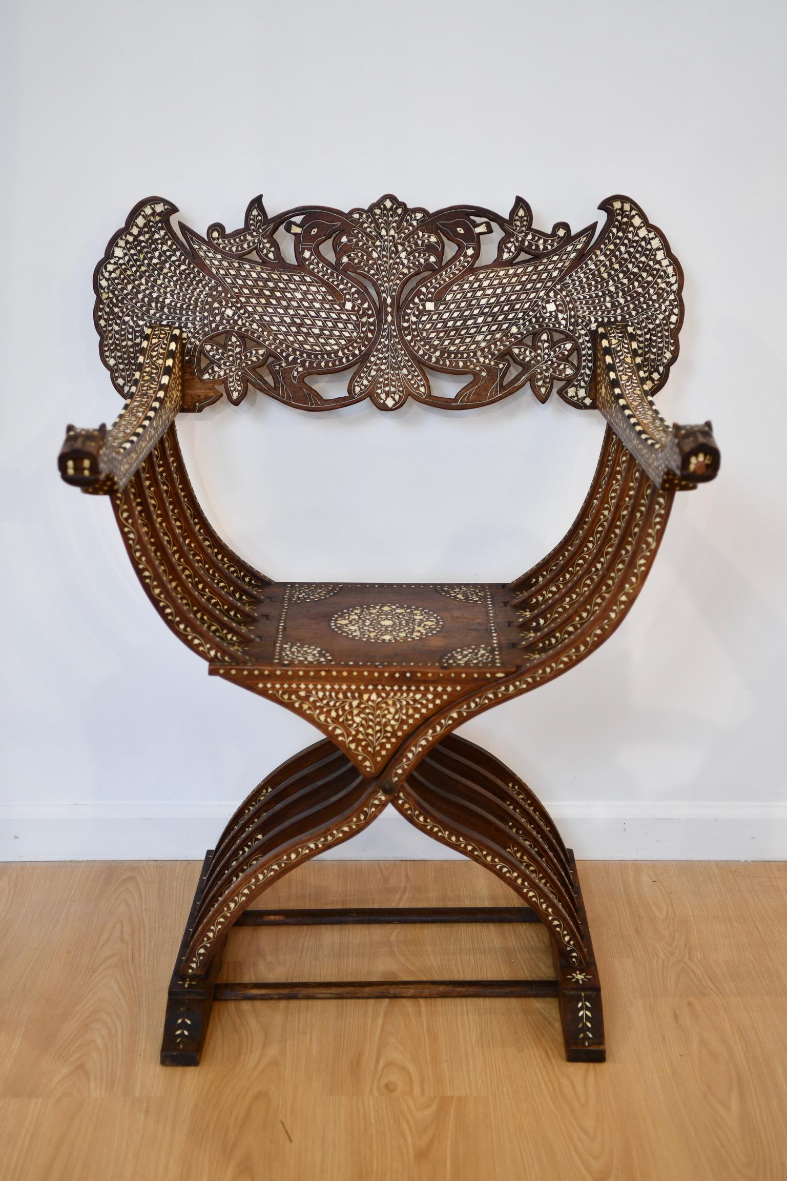 Syrian savonarola chair with elaborate mother of pearl inlay and etched faces at arms' end. Back and seat piece can be removed, pictured. Slight damage to the wood on back piece, also pictured. Dimensions: 37.5