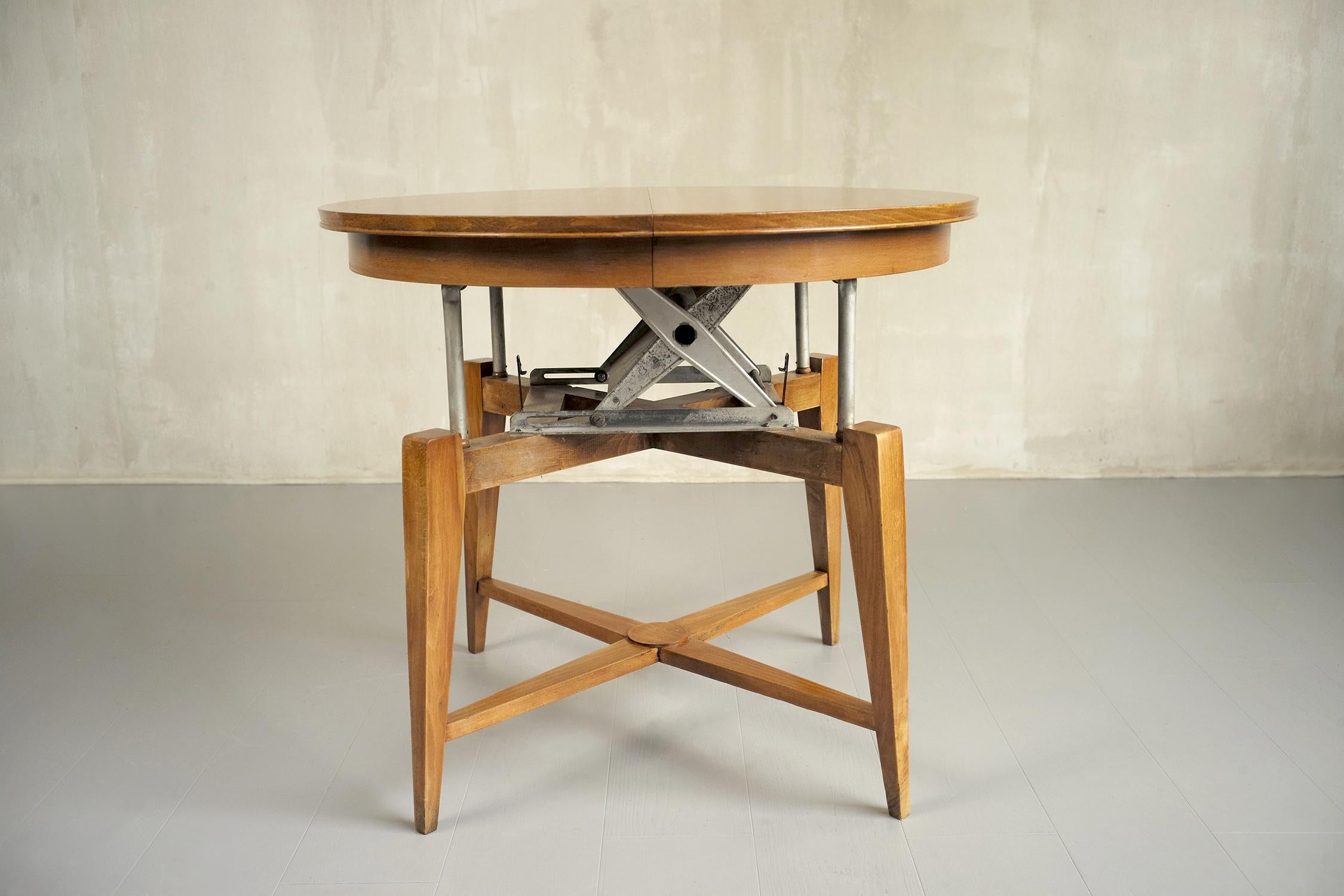 Table basse avec mécanisme en bois de cerisier, France 1950. Un système de pantographe permet de monter le plateau, qui se transforme alors en table à manger. Avec son extension, elle peut accueillir 4 à 6 personnes. Très bon état.