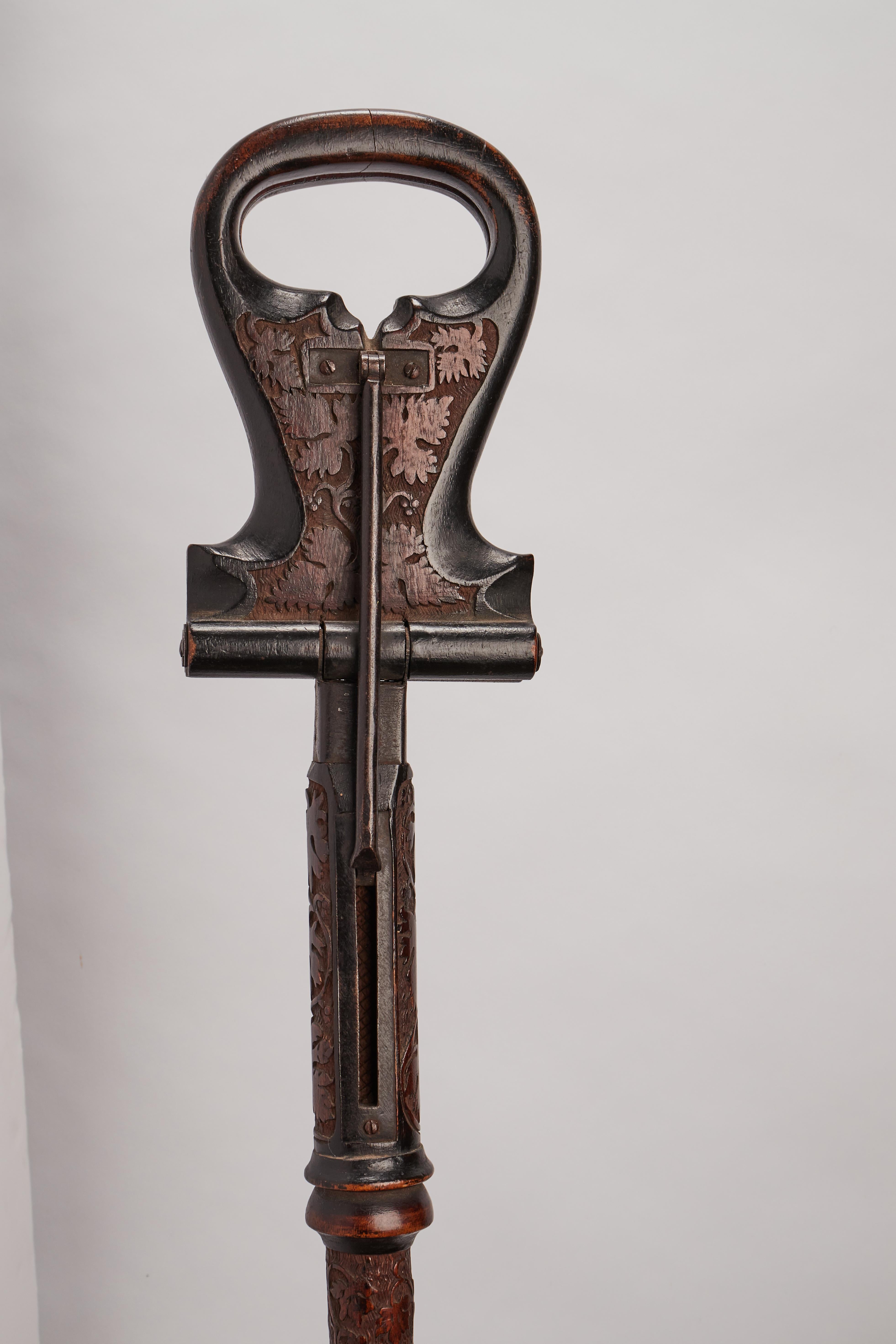 Gadget-System Folk Art walking stick: a stick with the seat function. Carved wooden seat and iron parts depicting the grape leaves and metal ferrule, France, circa 1880.