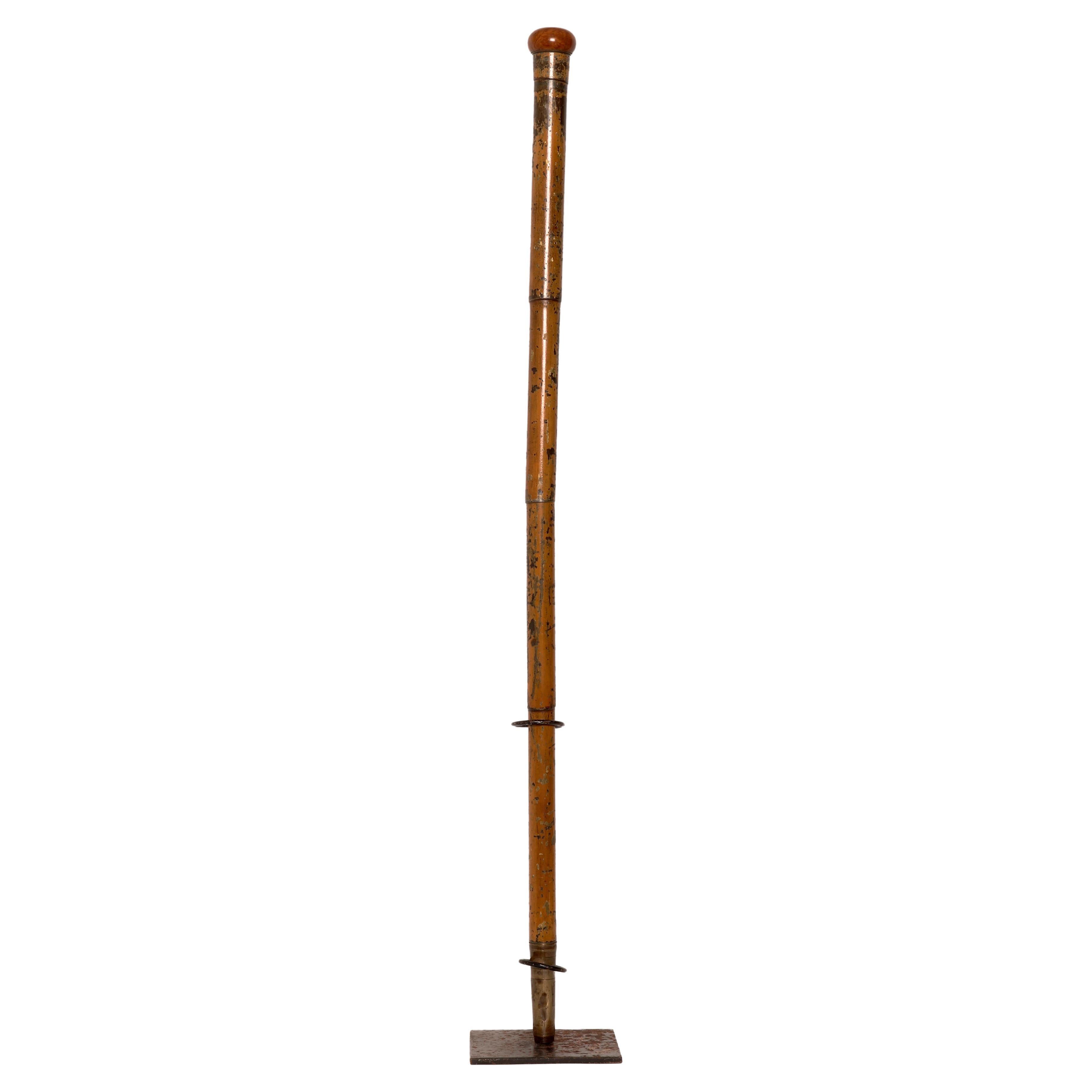 Gadget-System stick. The tip is made of iron and brass, high and decorated by a series of thin circles. The shaft is made entirely of painted brass and constructed to emulate a bamboo cane. The painting of the entire barrel completed everything. The