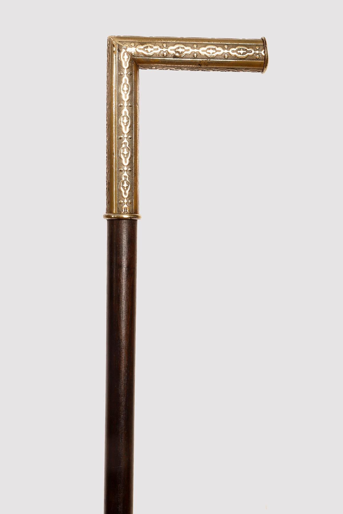 System walking stick with deer horn tip, santos wood shaft (Cesalpina Ferrea, Brazil). L-shaped handle in slightly silvered brass with smooth bands alternating with bands decorated with continuous motifs on a striped base. At the end of the