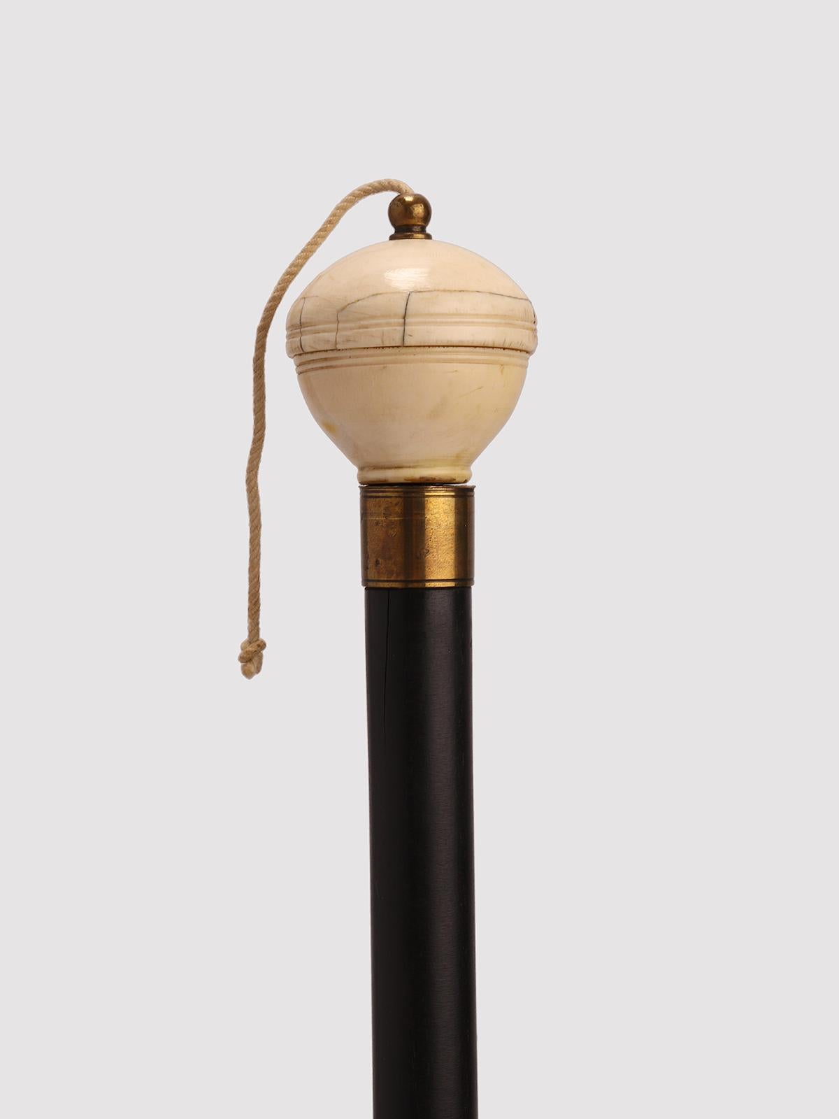 Bâton Gadget-Système : bâton ayant pour fonction de déterminer la direction verticale par rapport à un point précis. Corps en ébène, bouton en ivoire. A l'intérieur du bouton se trouve un fil à plomb. Pour l'utiliser, commencez par dévisser le