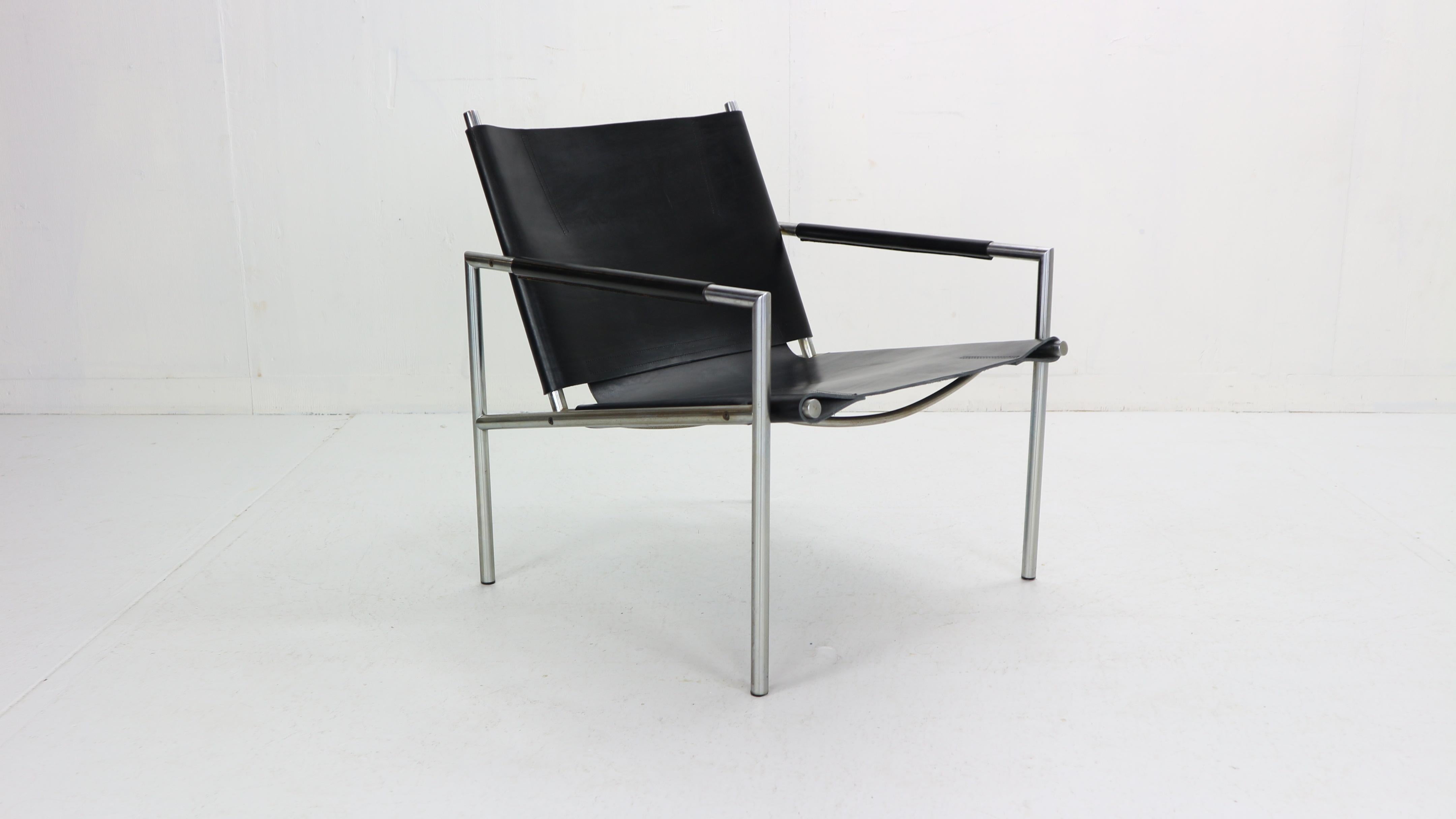 Model SZ02 armchair by Dutch designer Martin Visser designed for ’t Spectrum in 1965. 
The chair is executed in a black colour saddle leather and has leather upholstered armrest. 
The piece has great detailing of the saddle leather sling in the