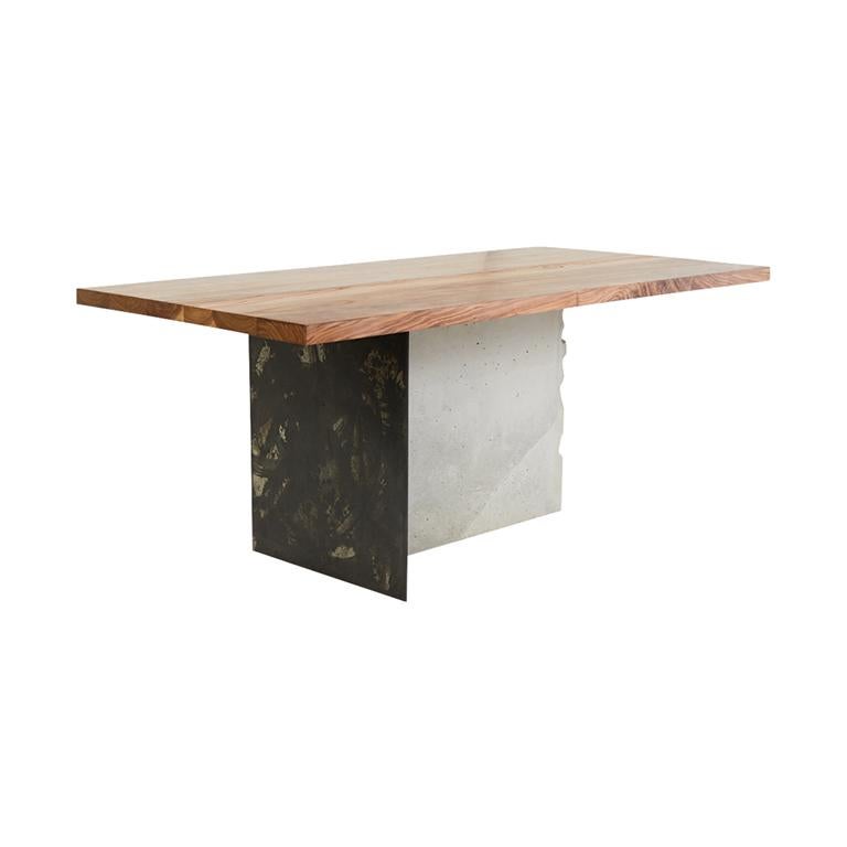 A solid walnut wood top rests on a base composed of Stefan Rurak Studio's unique patinated steel, joined with concrete. The leg is cast and then cracked by hand, revealing the rebar within. An abstract line drawing is etched into the Walnut top
