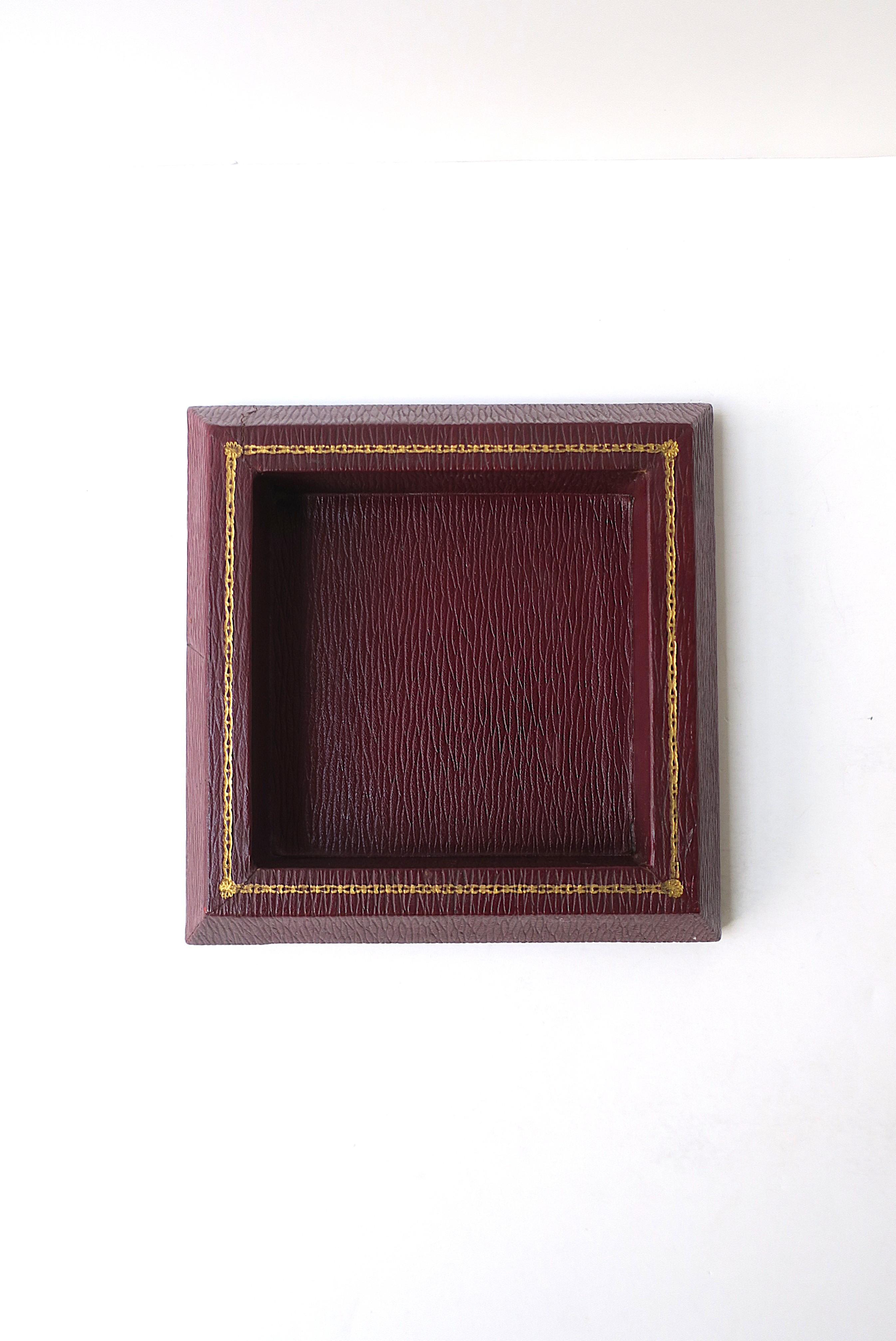 A square red burgundy textured leather jewelry catchall with gold tooling around top edge, by American luxury maker T. Anthony LTD., circa mid-20th century, England. A great catchall vide-poche for jewelry or other items on a desk, vanity,
