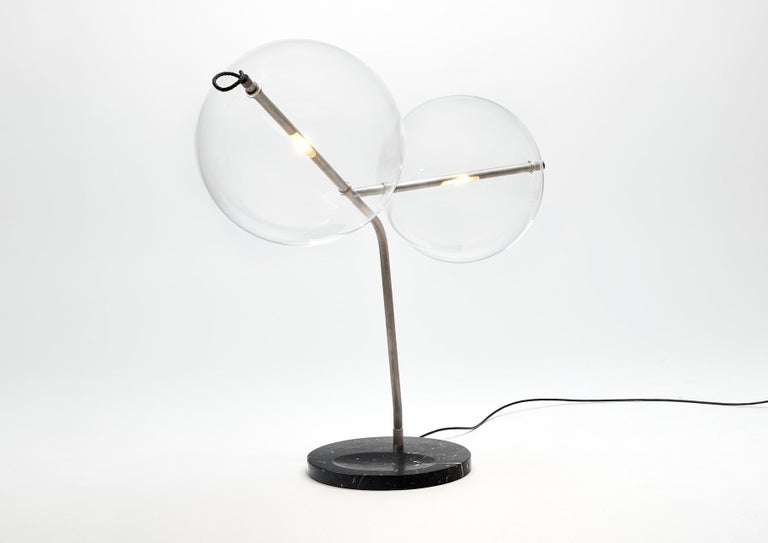 T-Bubble tries to define a more intimate space within the perimeter of the desktop. 
Two branches embrace the upper area, and the direction of each led light can be adjusted.
The light can be controlled and dimmed by touching the leather ring that