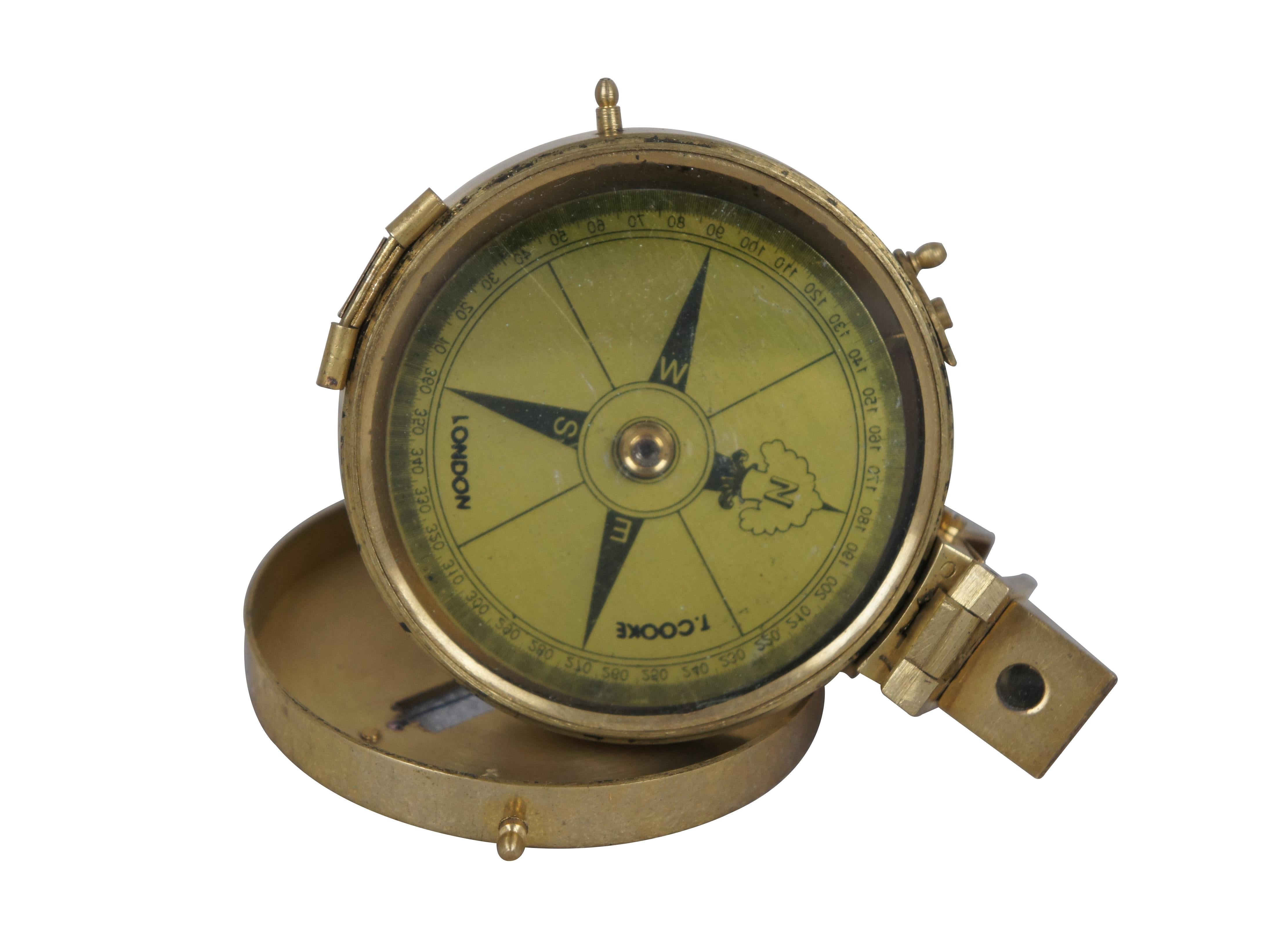 Vintage T. Cooke of London prismatic compass. Brass case with pierced sight line in the lid, folding prism, metallic gold tone face, and short stand able to be screwed onto a tripod for stabilization.

