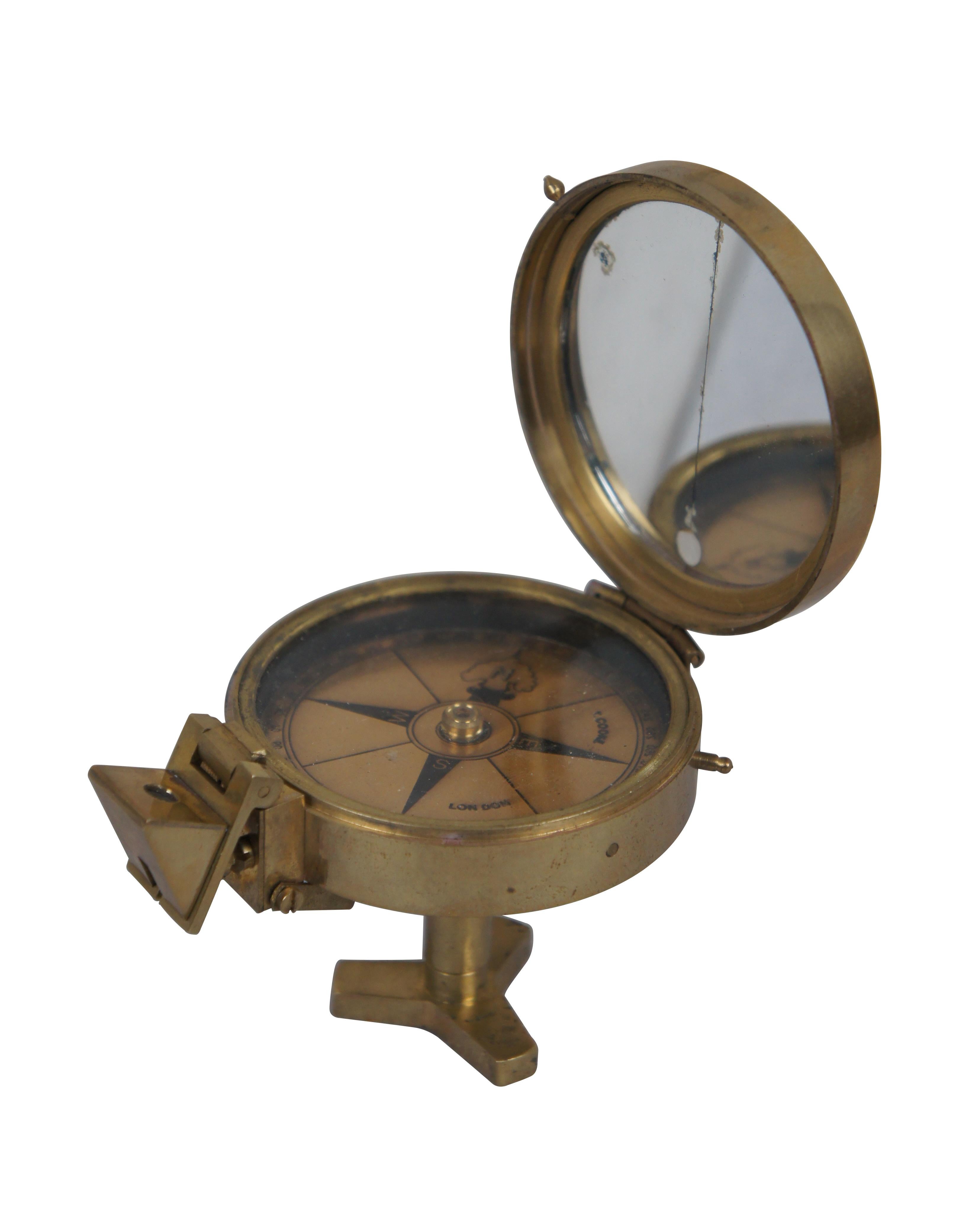 Vintage T. Cooke of London England prismatic compass. Brass case with mirrored lid interior, folding prism, metallic brass face, and short stand able to be screwed onto a tripod for stabilization.

