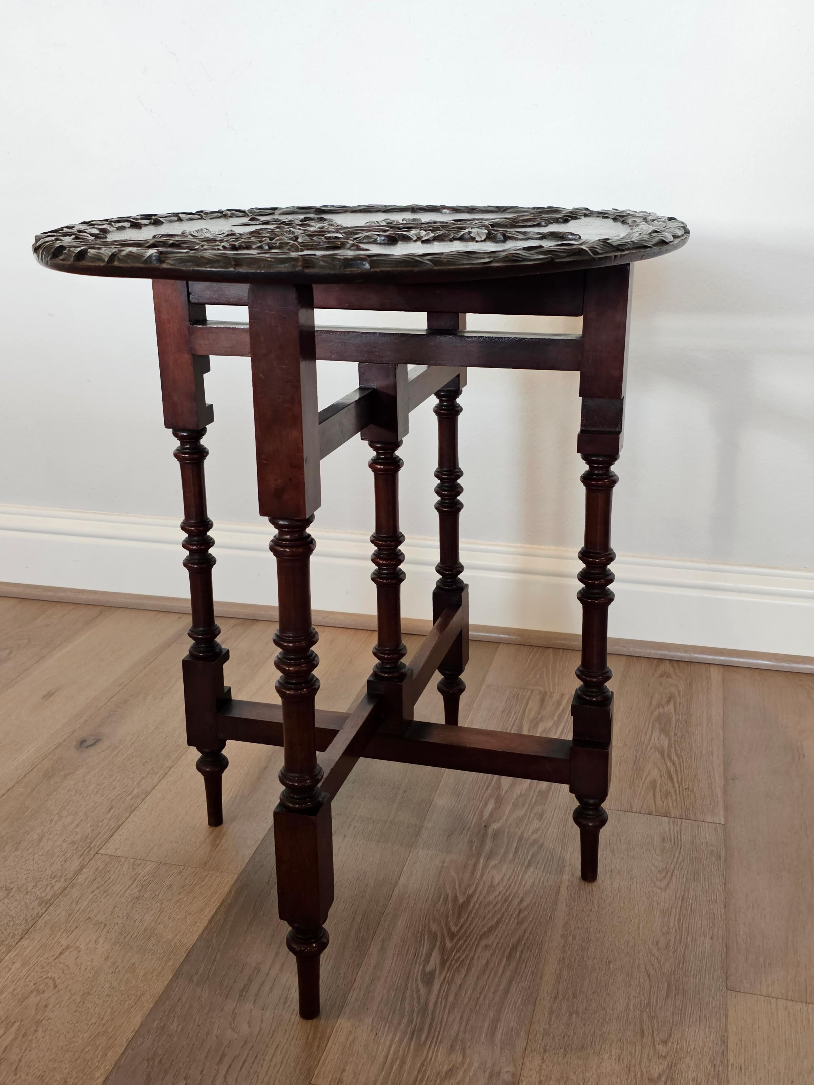 An antique English Victorian finely hand carved mahogany gateleg side table by Thomas Simpson and Son.

Born in England in the late 19th century, having a hinged oval tilt-top with intricate foliate relief carvings and incised detailing, folding