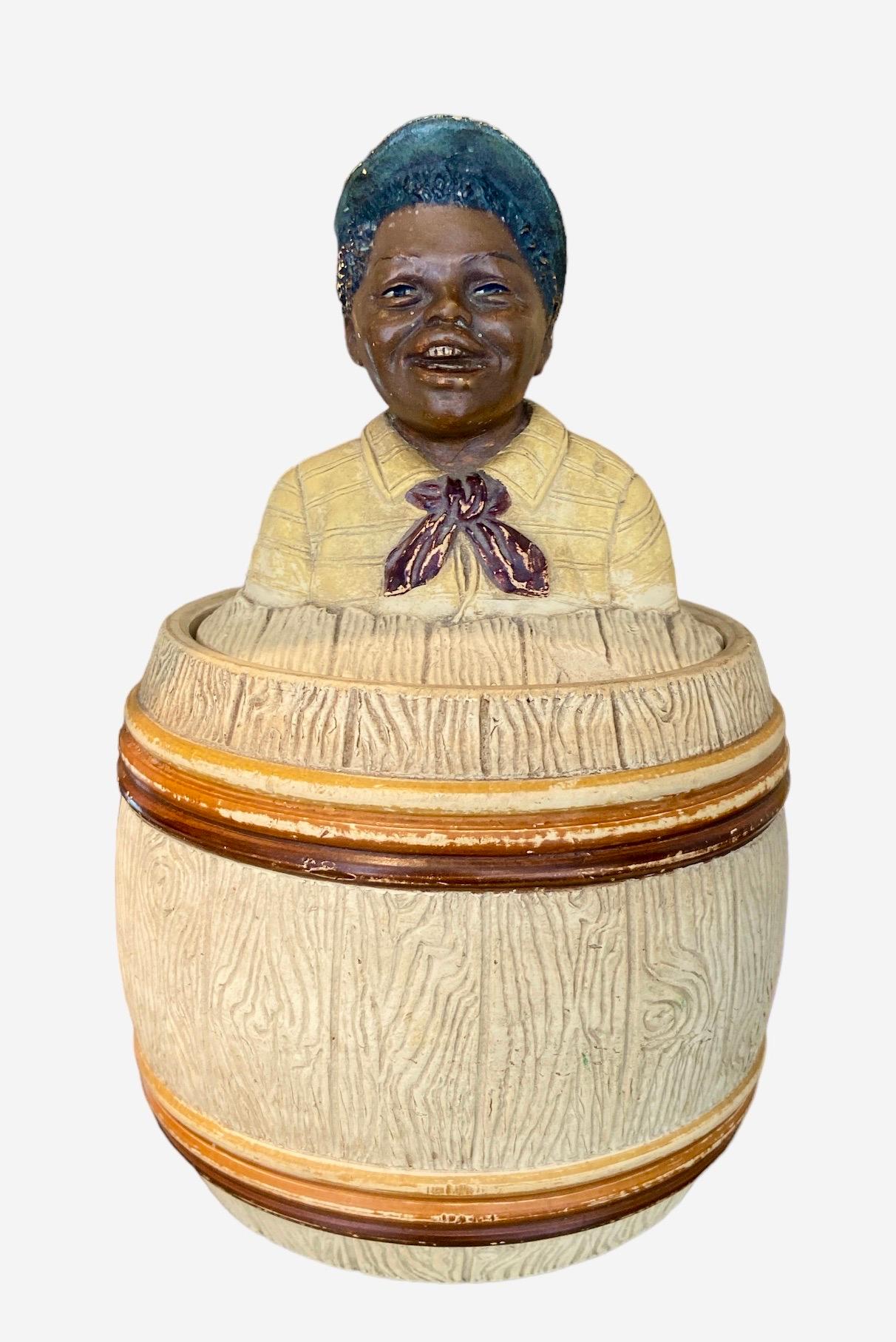 Das Tabaksglas hat die Form eines Holzfasses mit einem lächelnden kleinen Jungen darauf. Handbemalte Terrakotta. Höhe: 18 cm. Durchmesser: 12 cm.
