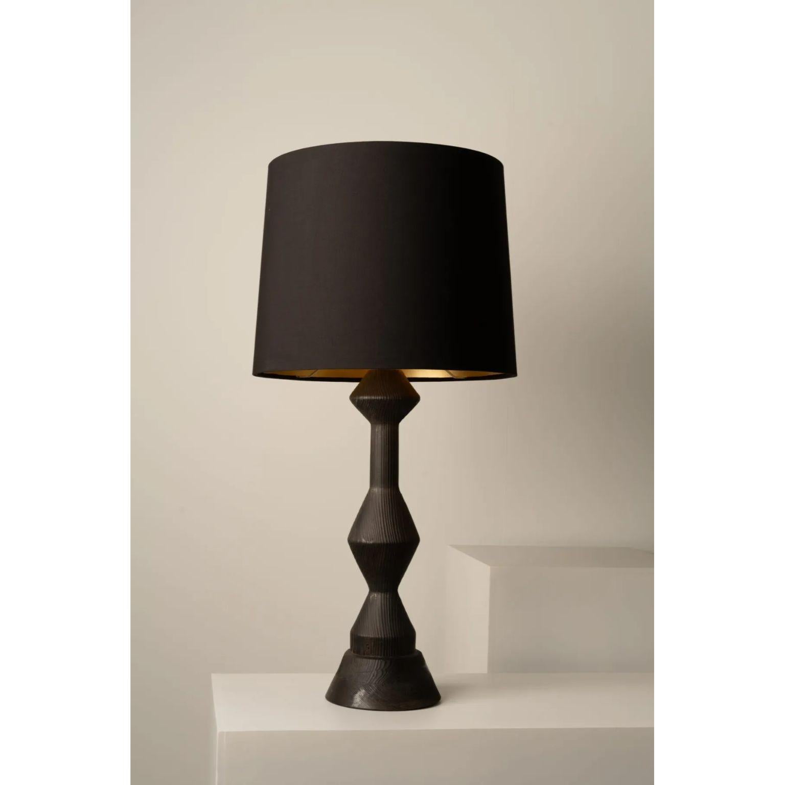 Tabachín Table Lamp by Isabel Moncada
Dimensions: Ø 51 x H 99 cm.
Materials: Fiberglass, linen, gold and turned pine wood.

The silhouette of Tabachín is categorical, straight lines that make up black cones and diamond shapes. The deep graphite