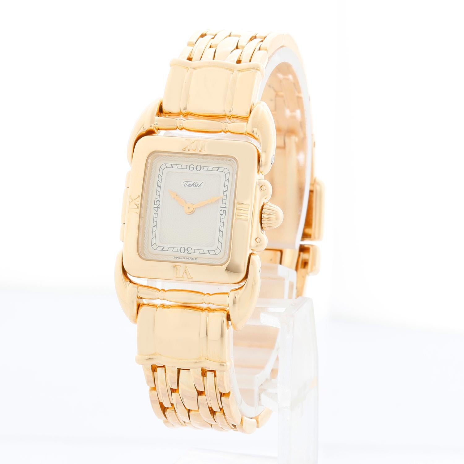 Tabbah Montre pour dames Saga Of Tabbah en or jaune 18 carats - Quartz. Saga de Tabbah. Or jaune 18 carats ( 22 x 21 mm) ; cornes ornées. Cadran crème guilloché. Bracelet en or jaune 18 carats ; convient à un poignet de 6 1/2 pouces. D'occasion avec