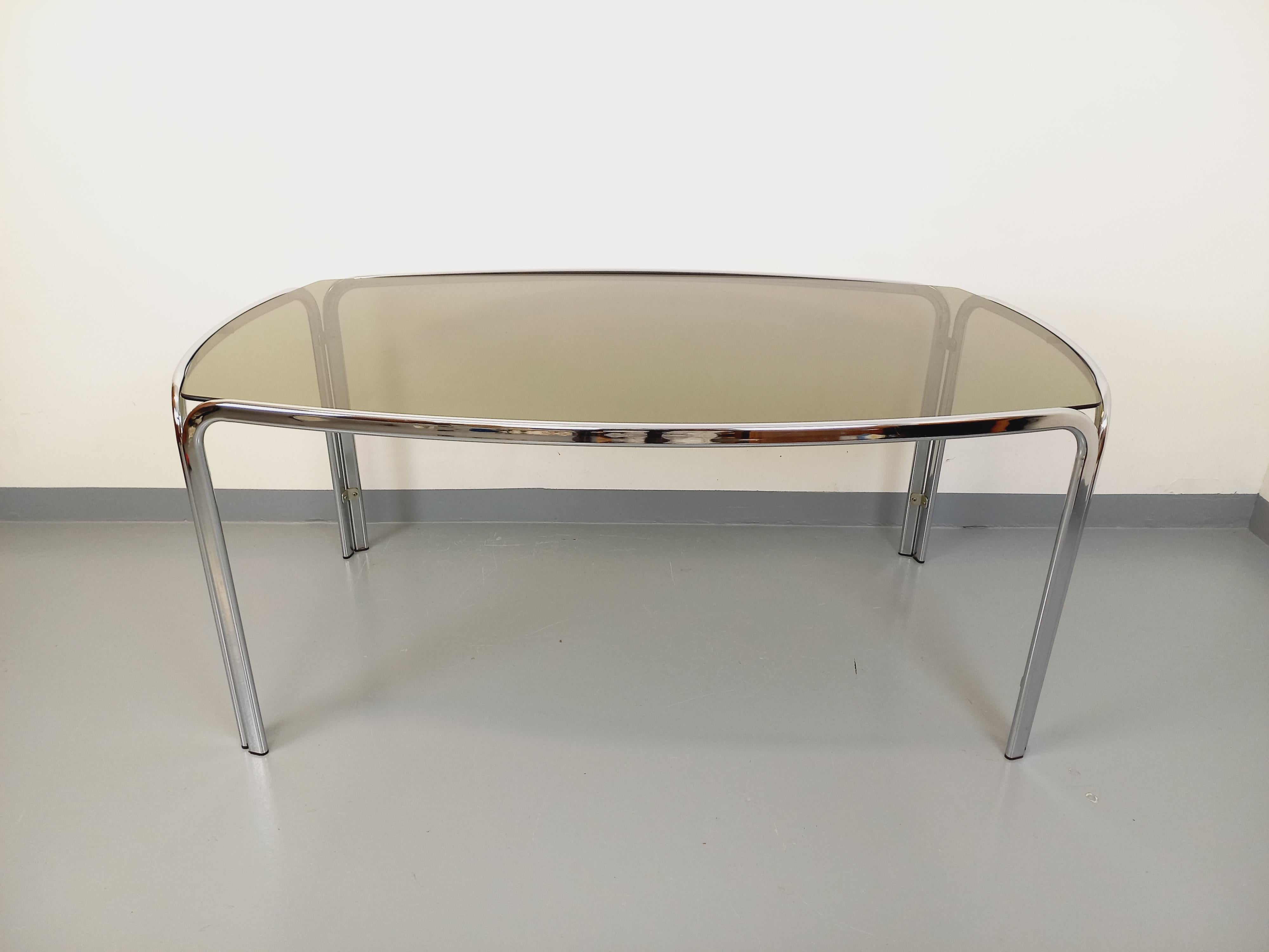 Table à manger vintage des années 70, style Space AGE, plateau rectangulaire incurvé en verre fumé, pied en métal chromé design, très bon état général avec quelques micro-rayures d'usage sur le plateau et quelques signes du temps qui passe sur le
