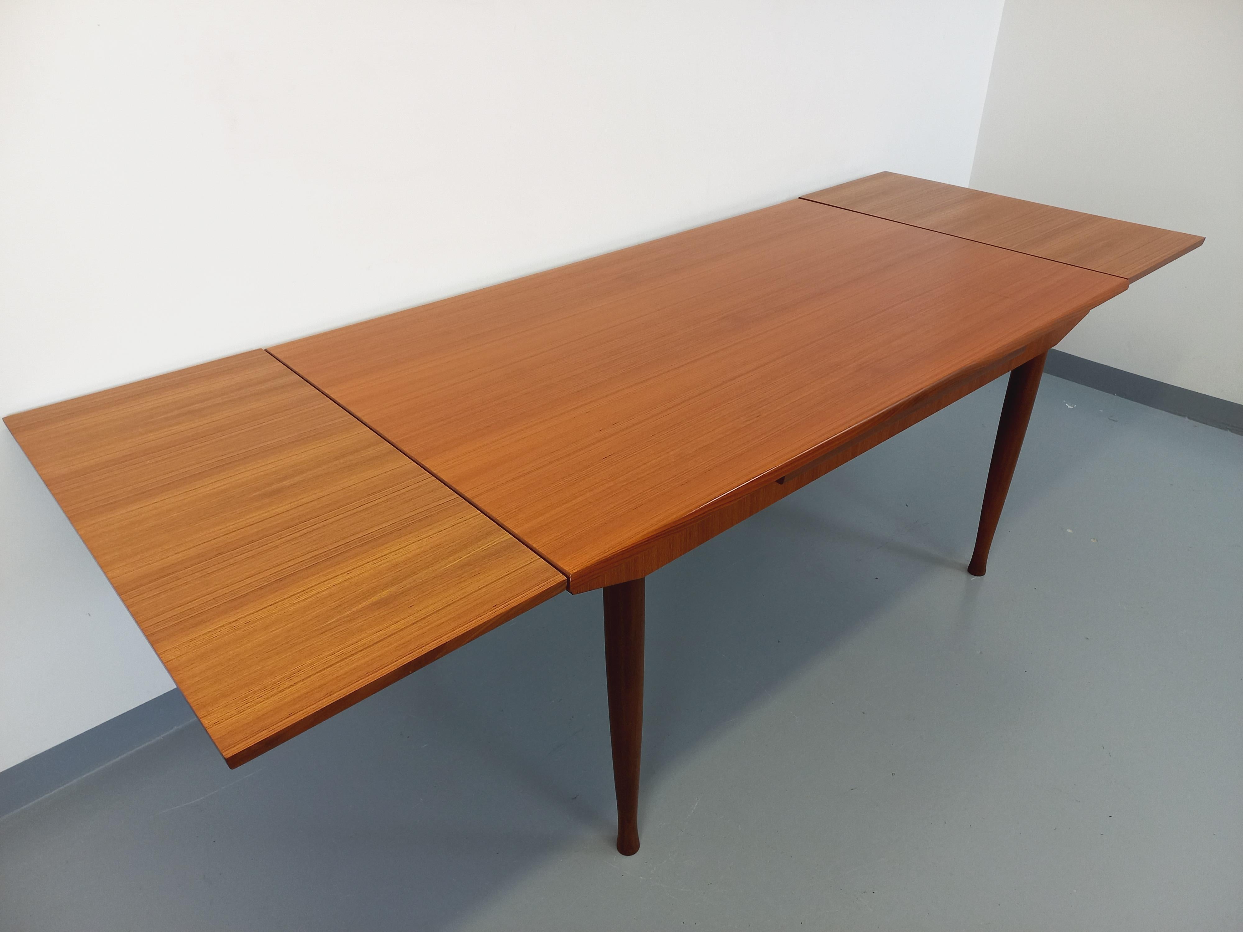 Table à manger rectangulaire vintage des années 50 60, en teck, plateau rectangle, avec deux rallonges intégrées aux extrémités, pieds compas évasés en bas, très bon état général avec seulement une légère rayure de surface sur le plateau.
Réf. 230