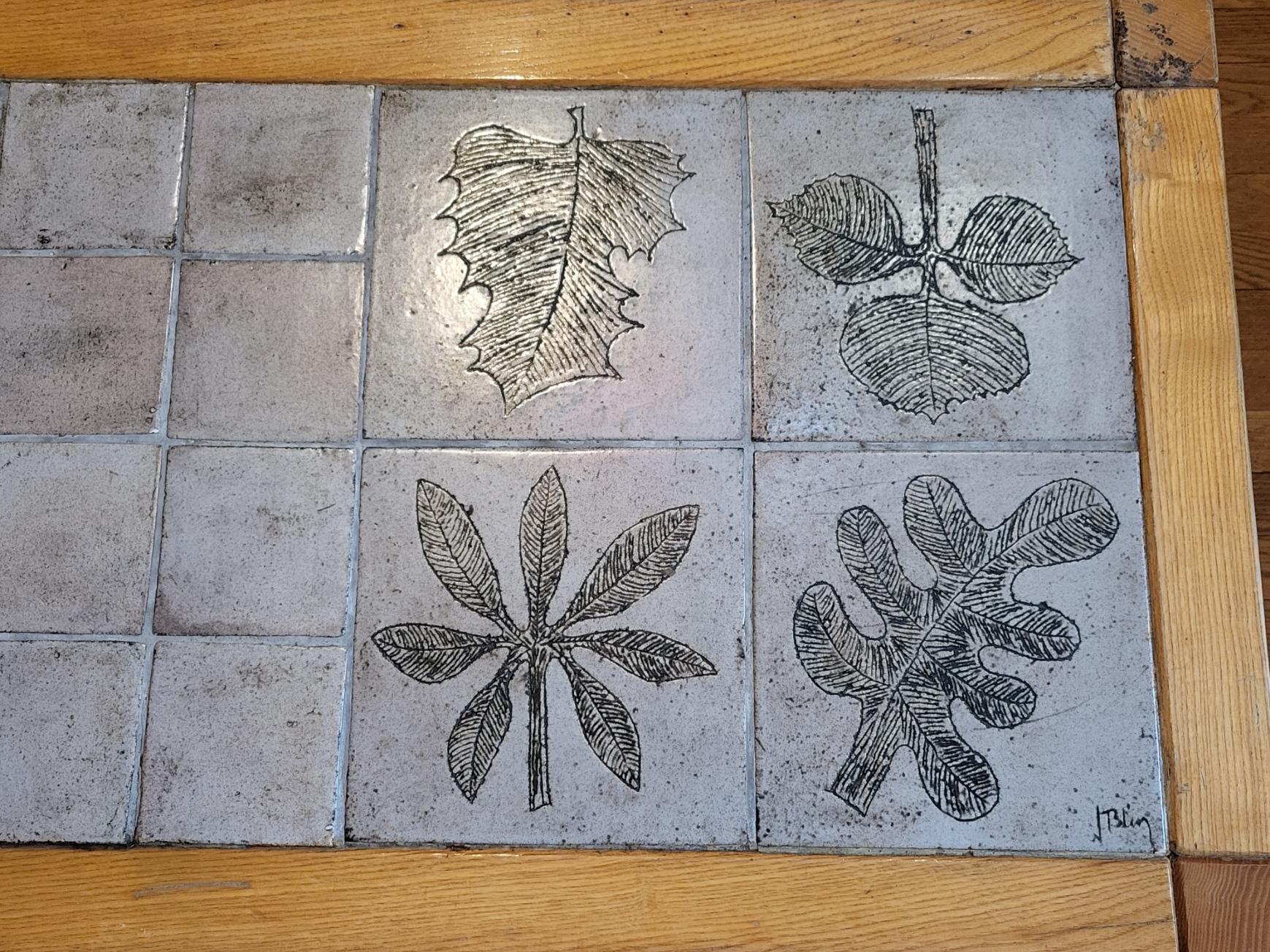 Table basse de Jacques Blin piètement quadripode en bois de chêne reposant sur quatre pieds quadrangulaires, plateau en carreaux, gris, beige de céramique émaillés et gravés de feuilles.
Jacques Blin arbeitet häufig mit anderen Künstlern und