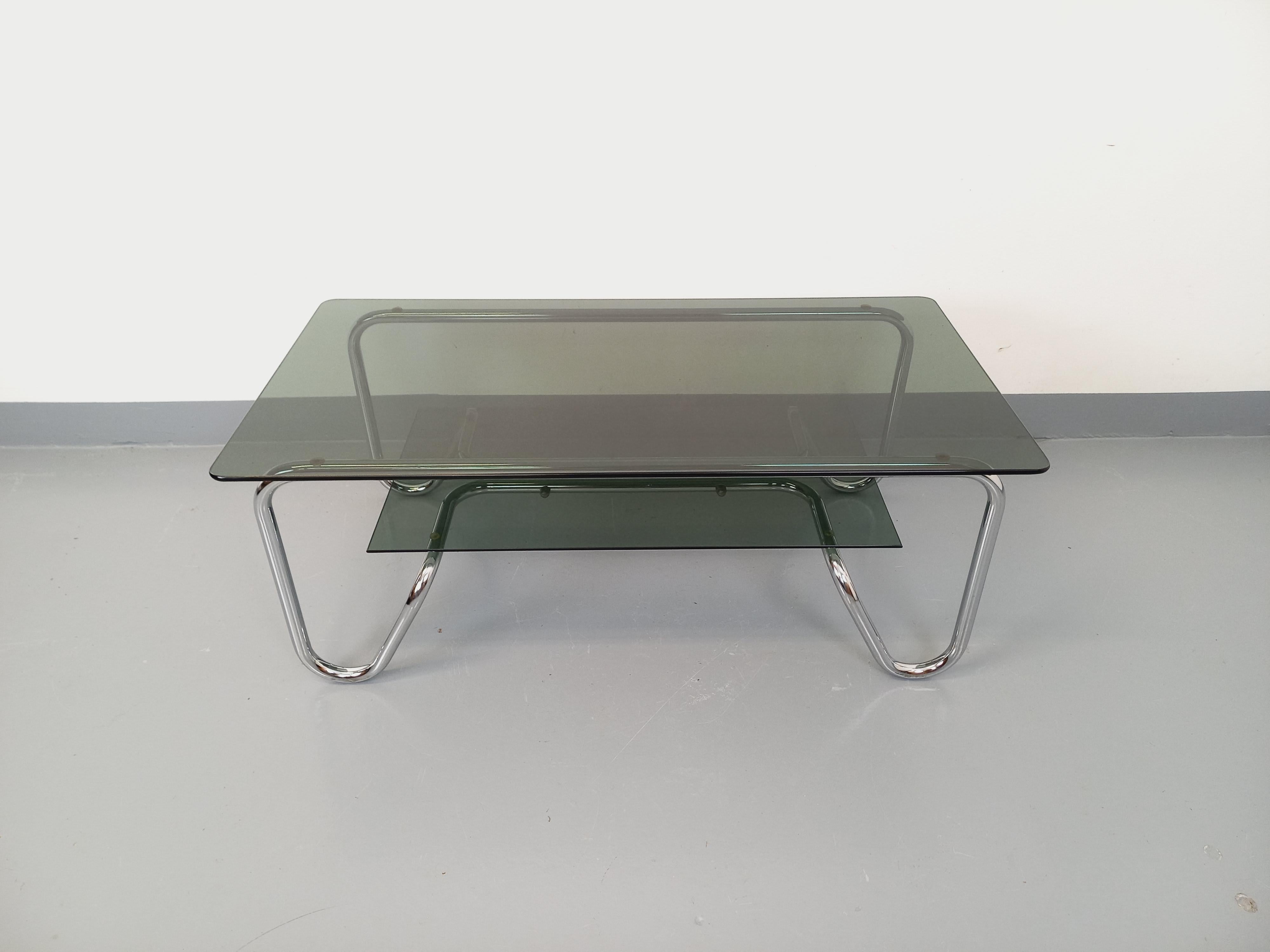 Table basse rectangulaire vintage des années 70, très beau design italien, 2 plateaux en verre fumé, structure tubulaire design en métal chromé. Très bon état général avec quelques très micro-rayures de surface sur le plateau supérieur.
Réf 250