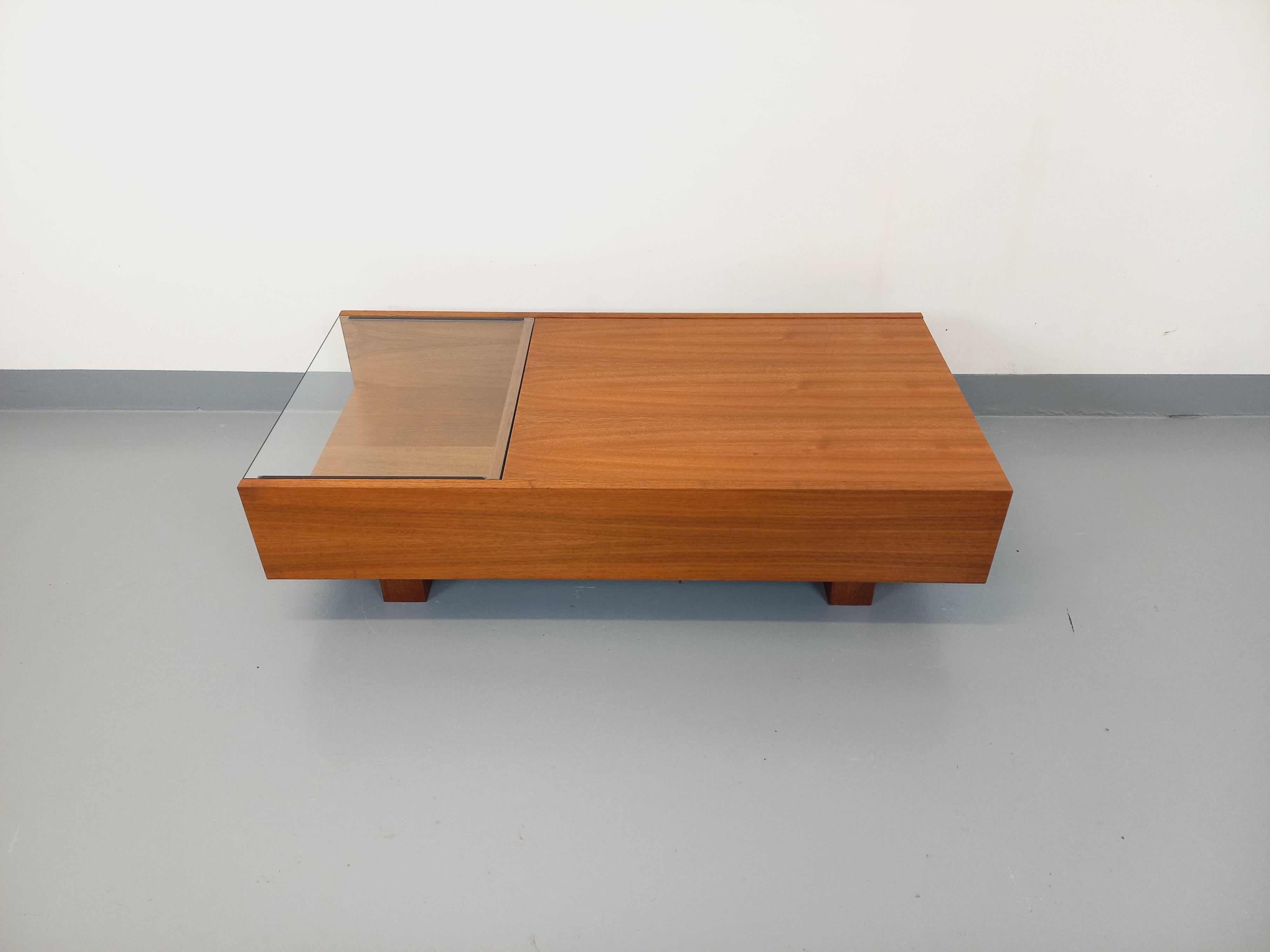 Table basse rectangulaire moderniste vintage des années 60 70, très beau design en teck et verre transparent, 2 niches ouvertes extérieures, et 1 coffre intérieur grâce à un plateau coulissant. Très bon état général avec quelques signes et marques