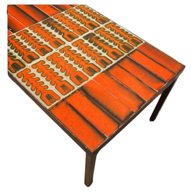 Roger Capron (1922-2006) / Vallauris : Table basse vers 1960, plateau rectangulaire composé de 56 carreaux dont 32 rouge noir et 24 avec motif végétaux rouge sur fond verdâtre, enchâssés dans une structure métallique à 4 pieds, signée, parfait état