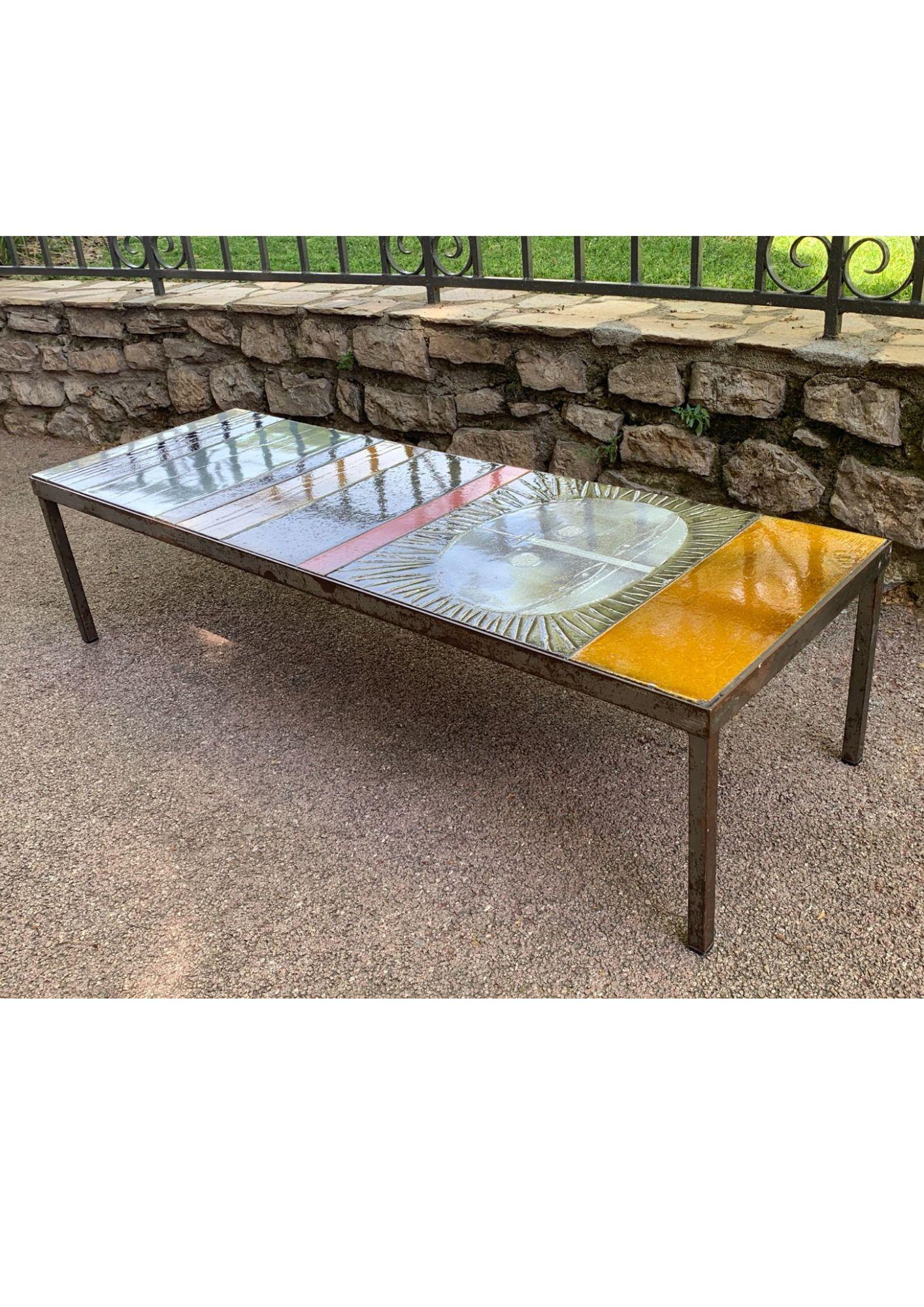 This coffee table combines the timeless elegance of Mid-Century Modern style with the exceptional mastery of ceramics. Its meticulously assembled glazed ceramic tile top features a striking sunburst pattern, composed of vibrant hues such as golden