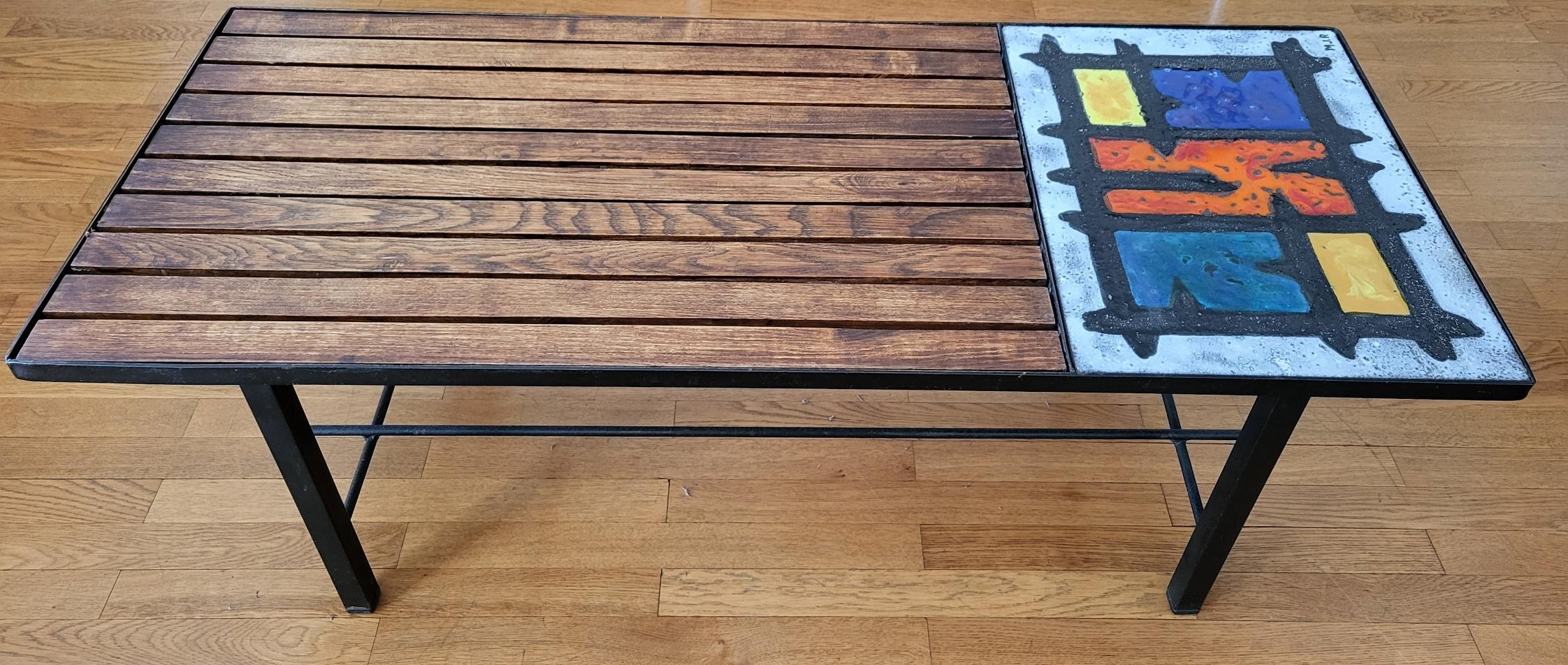 Sublimez votre intérieur avec la table basse Vallauris de Madoura, dont la structure en métal noir est accompagnée d'un plateau mixte alliant une partie en bois lamellé et une section en céramique ornée d'un motif abstrait multicolore, signé MJR. Ce