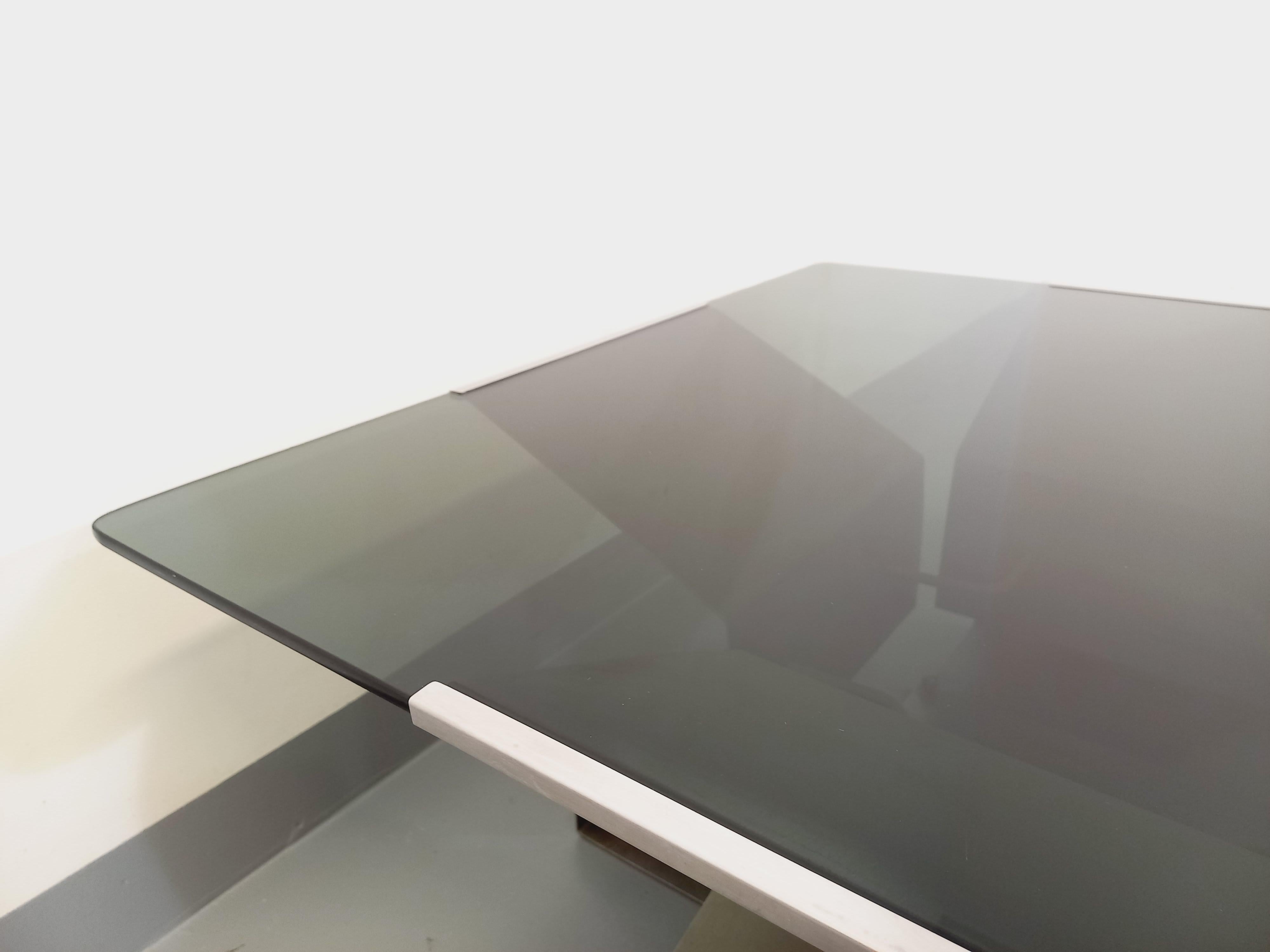 Grande table basse vintage des années 70, du designer français François Monnet pour Kappa, piétement design en acier brossé plié et courbé, grand plateau carré aux angles arrondis en verre fumé. Design/One, très bon état général avec quelques