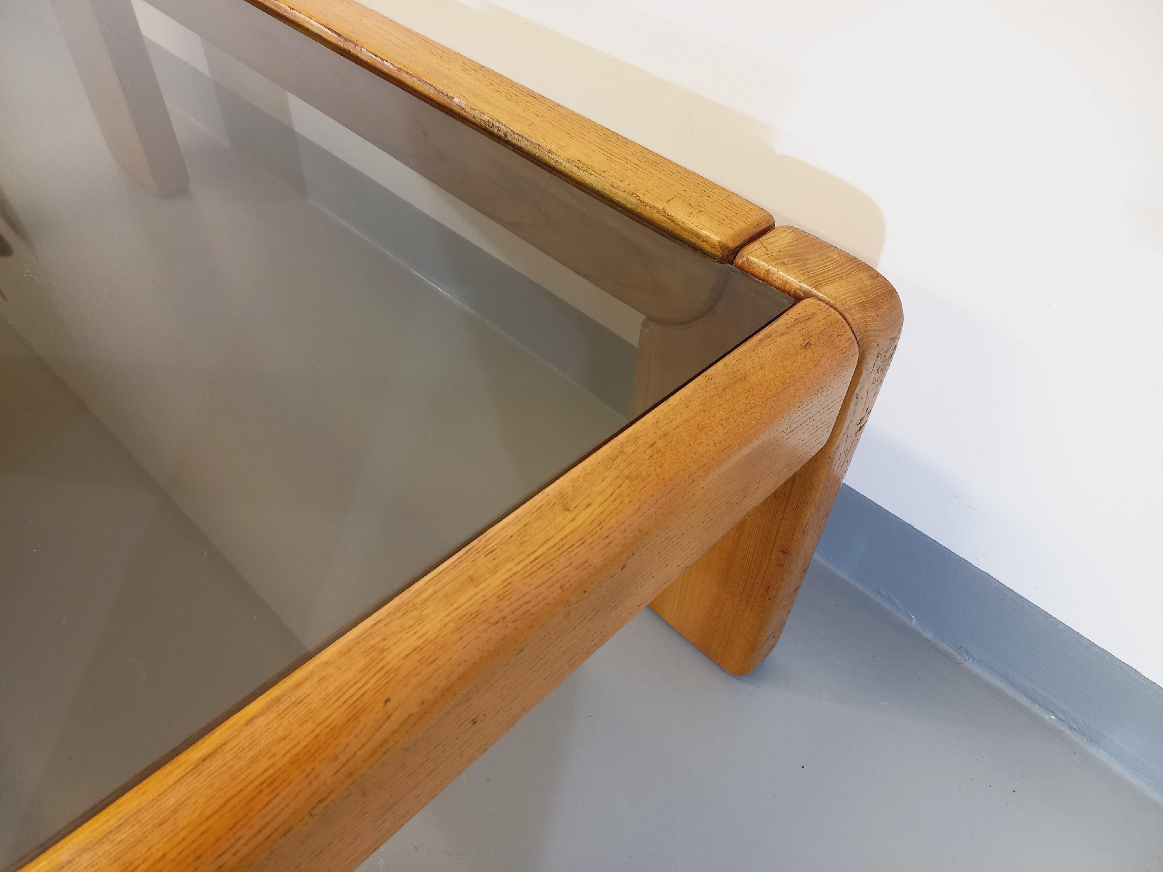 Table basse rectangulaire vintage des années 70 80, Maison Regain, pied et structure en orme blond, plateau en verre fumé rectangle, beau design, très bon état général avec le charme et la patine du temps qui passe sur le bois et quelques