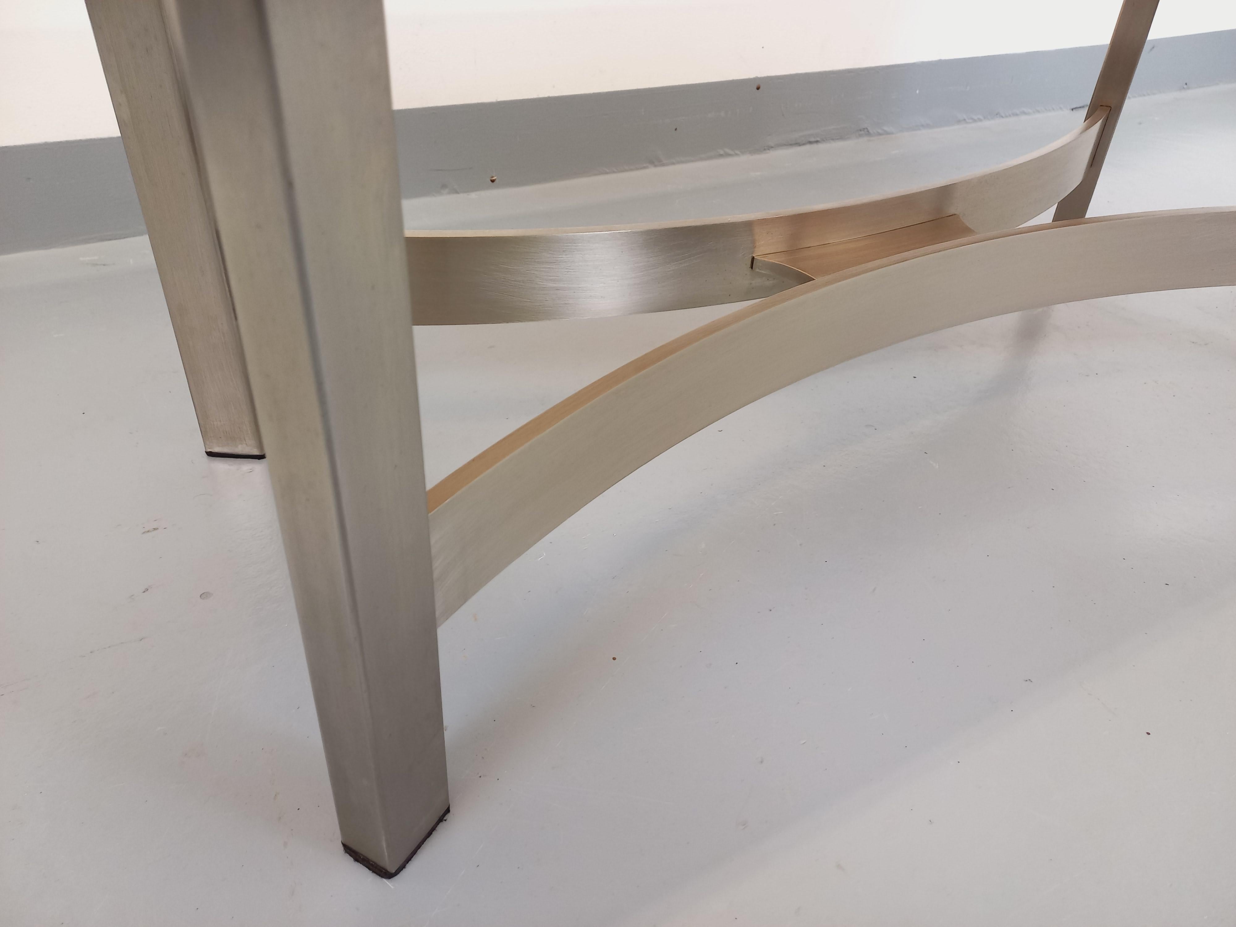 Grande table basse vintage des années 70, dans le goût des designers Vittorio Introini, Paul Legeard ou Boris Tabacoff pour Roche-Bobois, plateau rectangulaire en verre fumé, pied en fonte d'aluminium brossée au design en arcs de cercle, très bon