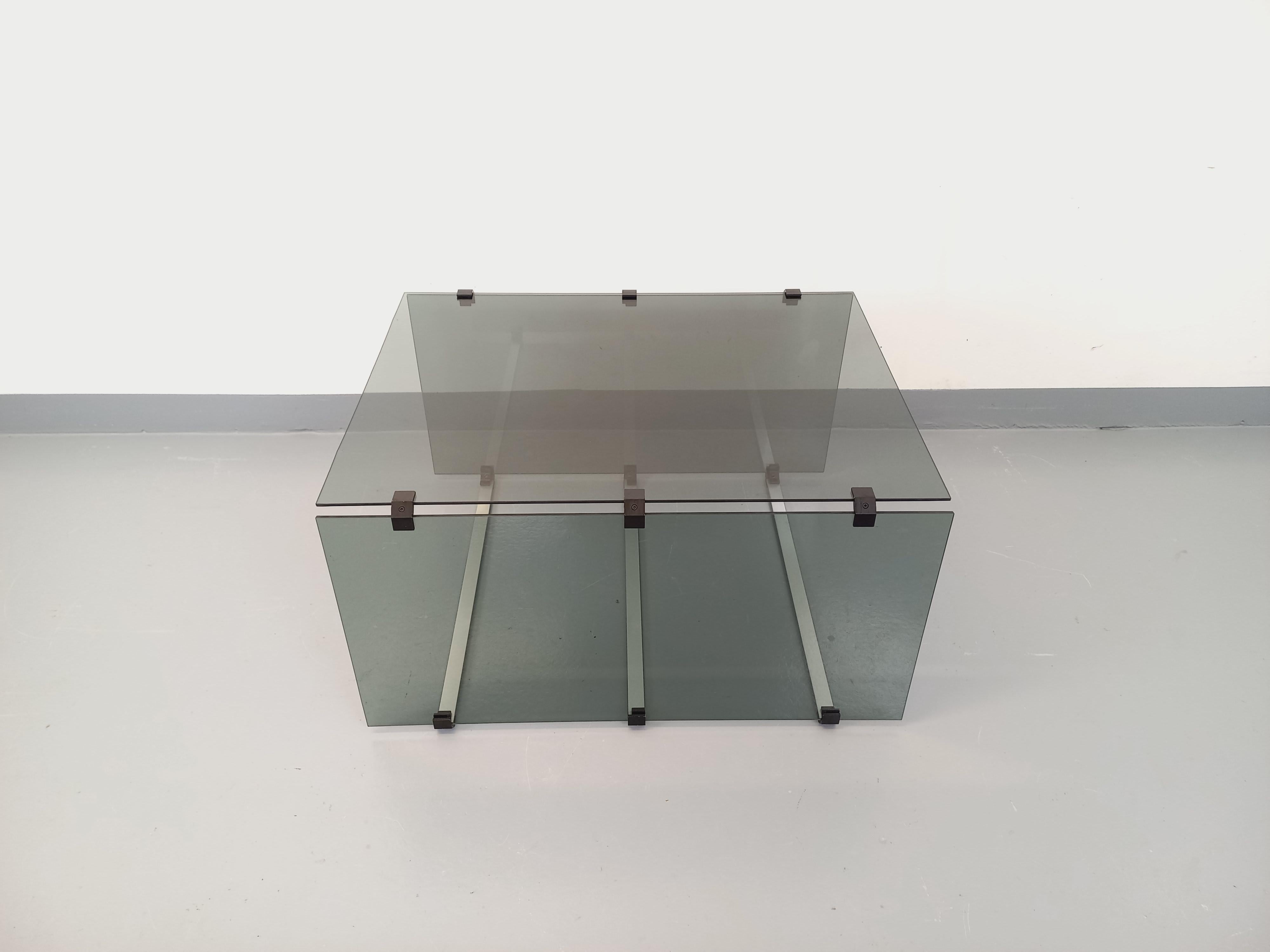 Table basse vintage des années 70, design original dans le goût des designers Gallotti & Radice, plateau et 2 côtés rectangulaires en verre fumé, supports en fonte d'aluminium, éléments de jointures en métal noir, très bon état général avec un éclat