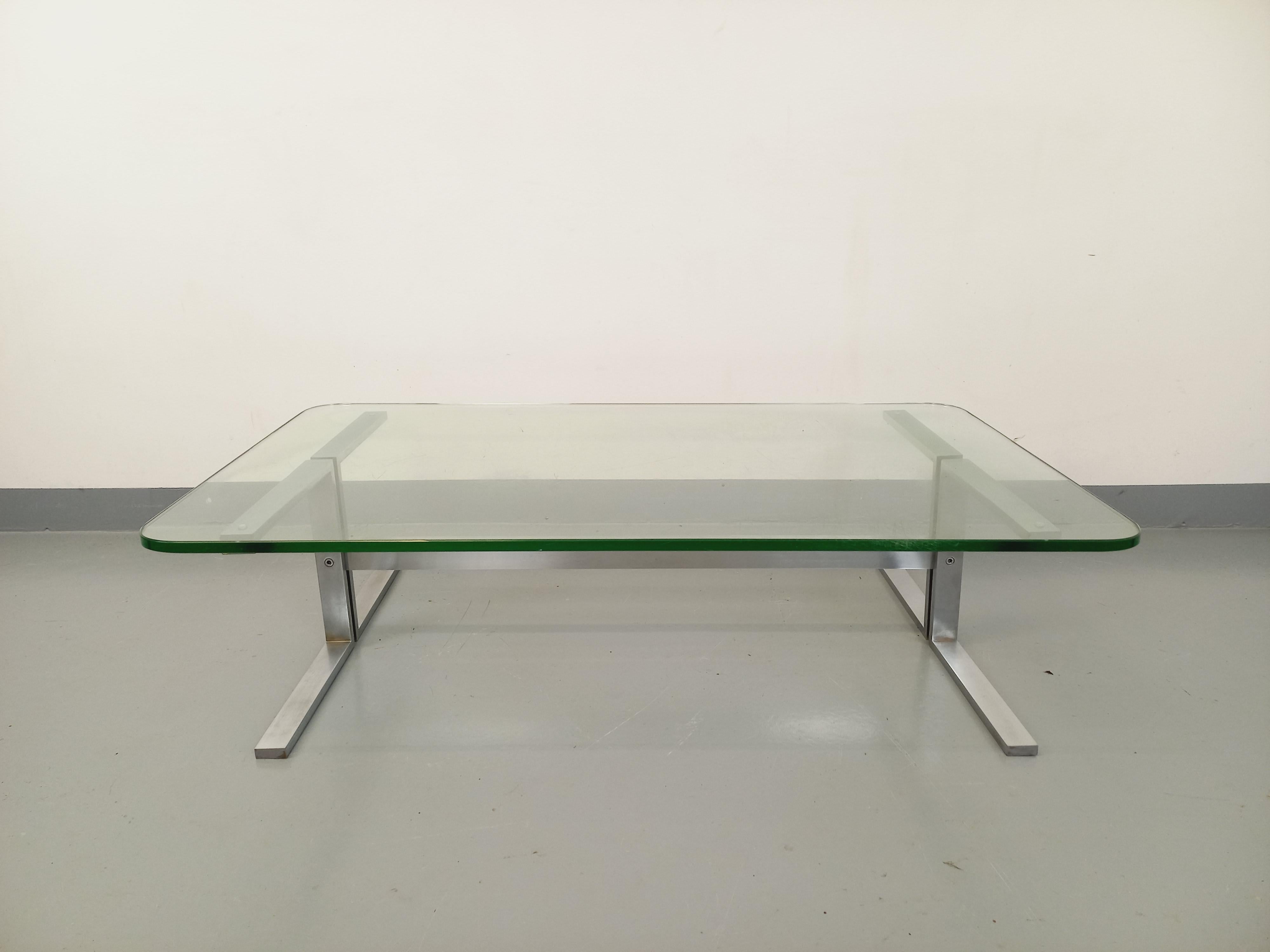 Grande table basse vintage des années 70 style Roche Bobois, plateau rectangulaire aux angles arrondis en verre épais transparent, pied en fonte d'aluminium design. Bon état général, métal chromé en très bon état général, verre en bon état avec des