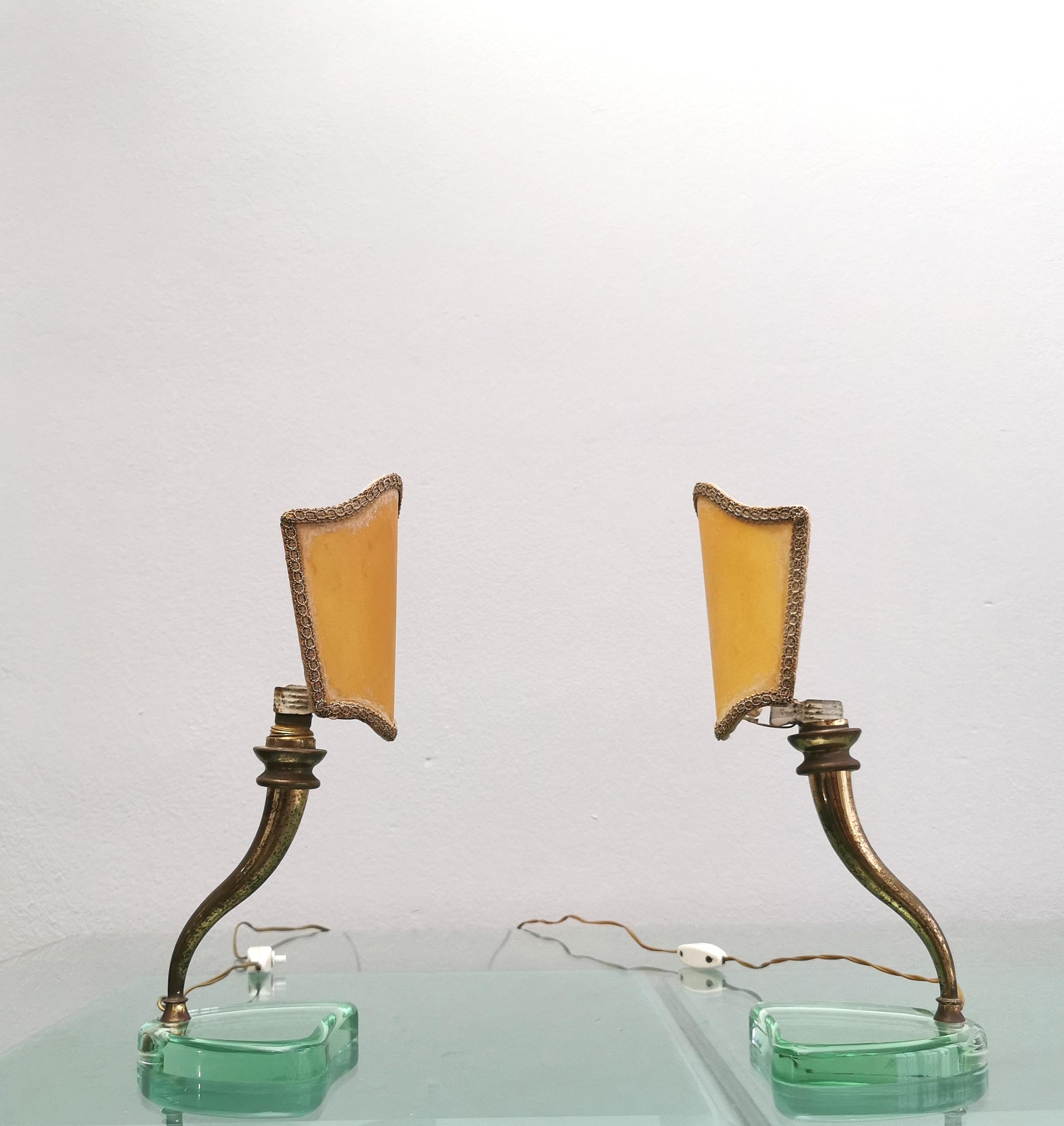 Set of 2 bedside or table lamps designed by the well-known Italian designer Emilio Lancia and produced in the 1940s. Each single lamp has been made with a very thick aqua green crystal glass base, brass structure and beige parchment diffuser with