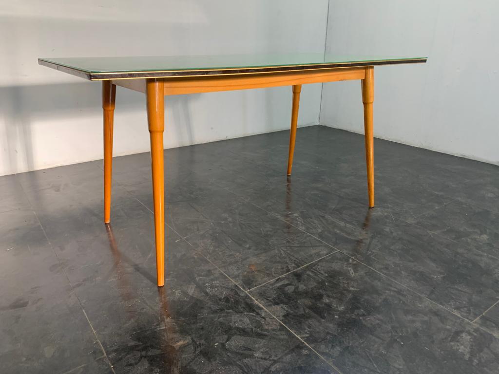 Table 50's profiled under top with black lacquered profile with brass edges the wood is beech, the top in aqua green glass. Under the top has the manufacturer's mark illegible. Light wear due to age and use. Small chip and slight lack of color on