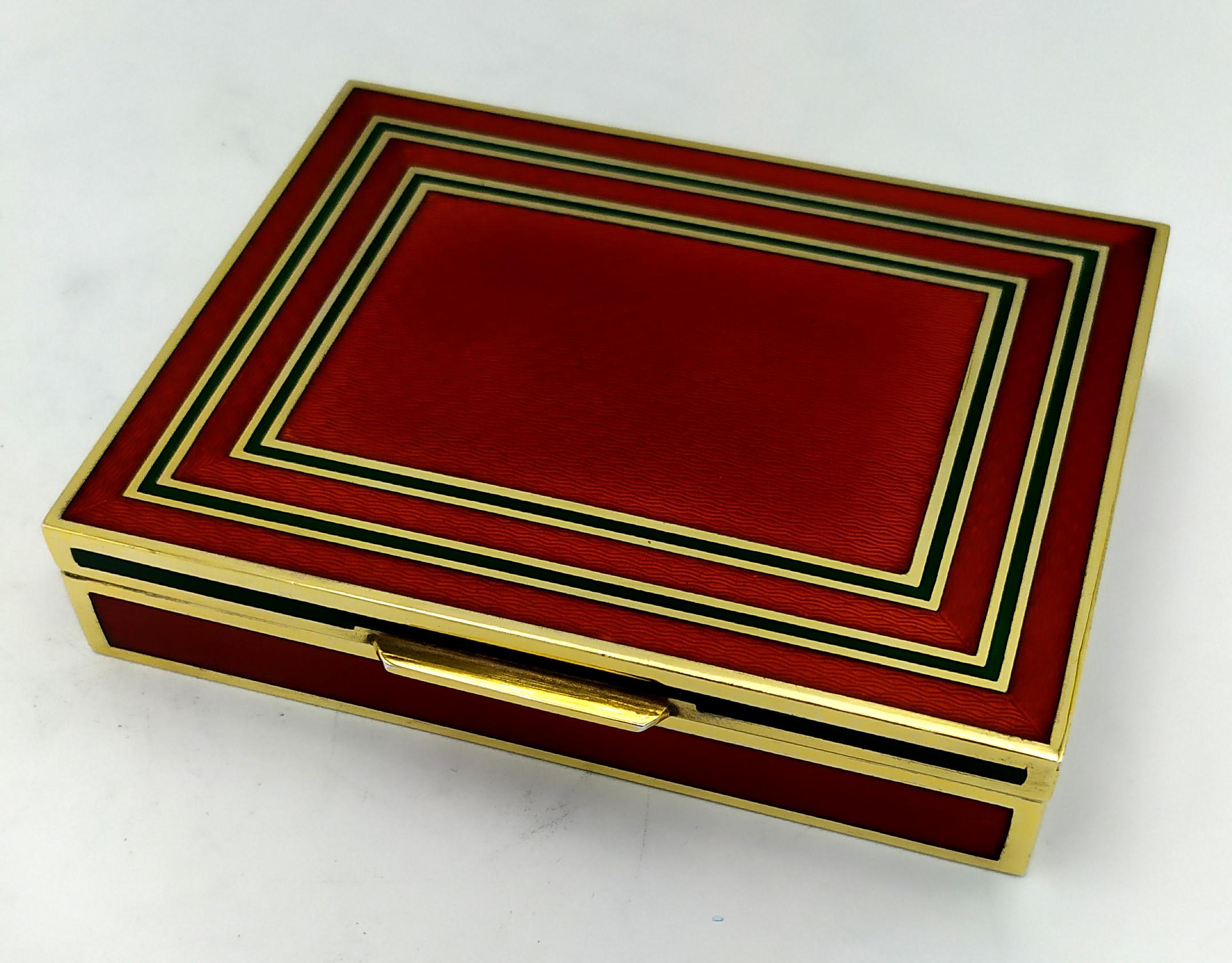 Caja de mesa rectangular de plata de ley chapada en oro 925/1000 con rayas de esmalte al fuego translúcido sobre guilloché, en dos tonos de rojo rubí y verde esmeralda, de estilo contemporáneo moderno. Medidas cm. 10 x 12,8 x 2,5. Peso gr. 569.
