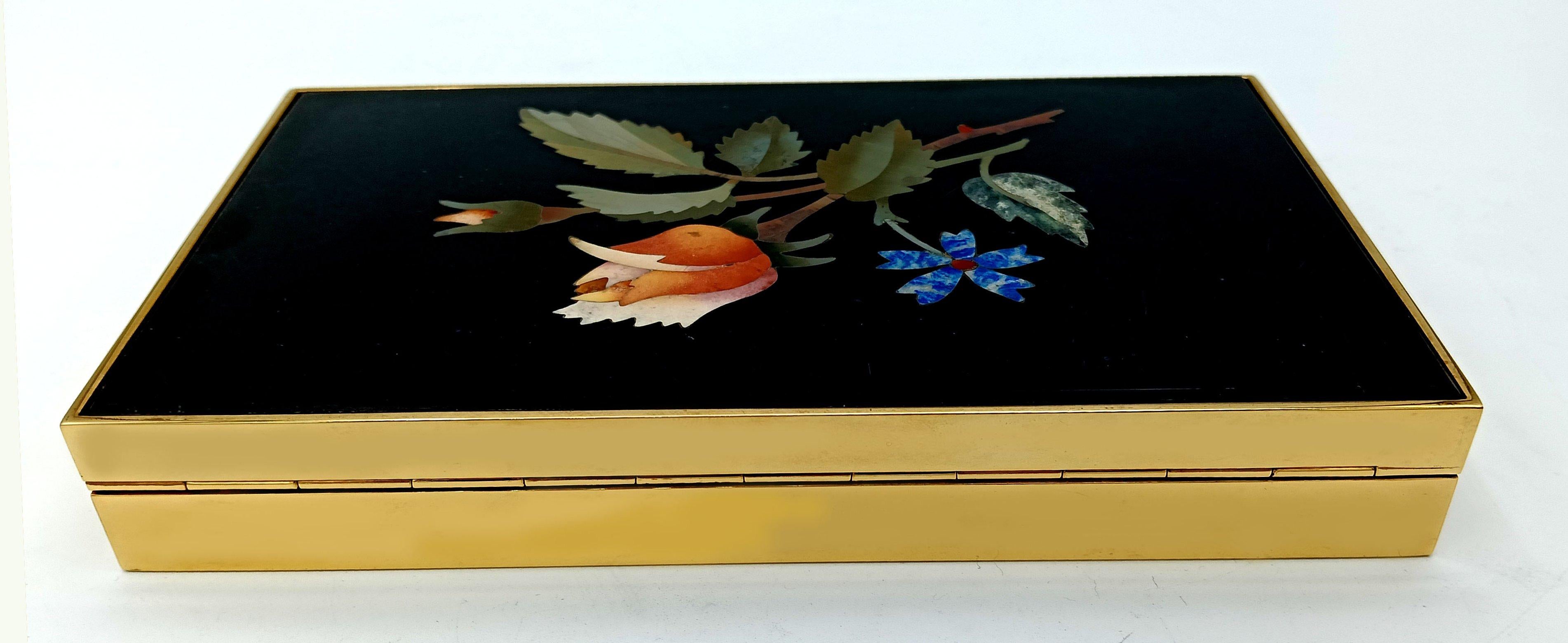 Rectangular box in 925/1000 sterling silver gold plated, smooth on the sides. On the lid, a plate with a fine floral mosaic of semiprecious stones made with the “commesso fiorentino” technique created in 1400 in the “Opificio delle Pietre Dure”