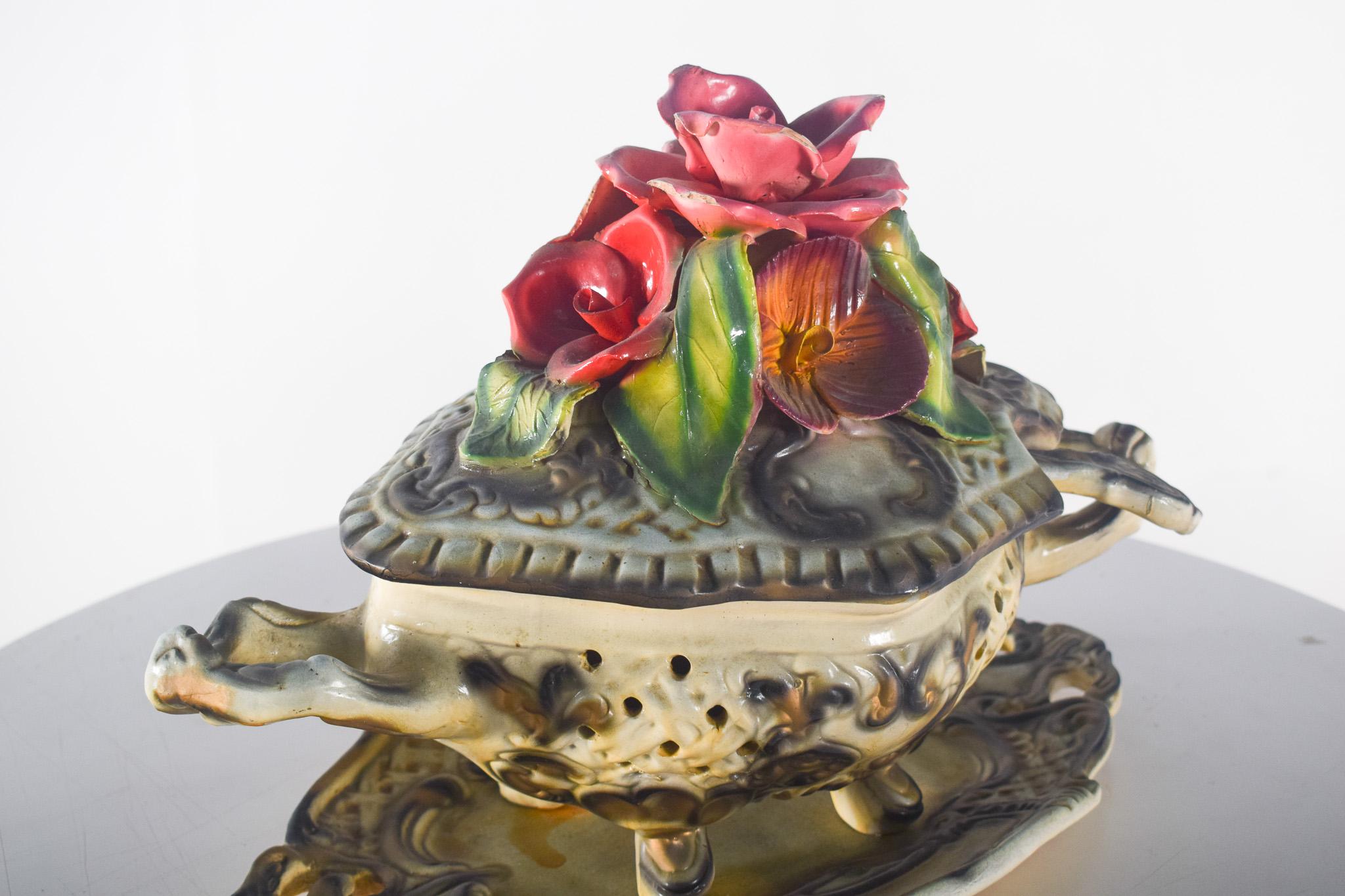 Centro de mesa, sopera con concha, en loza portuguesa. Decoración exuberante, con un cuerpo ricamente decorado con relieves en tonos crema y marrón, orificios que sirven de respiraderos para que pueda contener popurrí y dejar que emane el aroma. Las