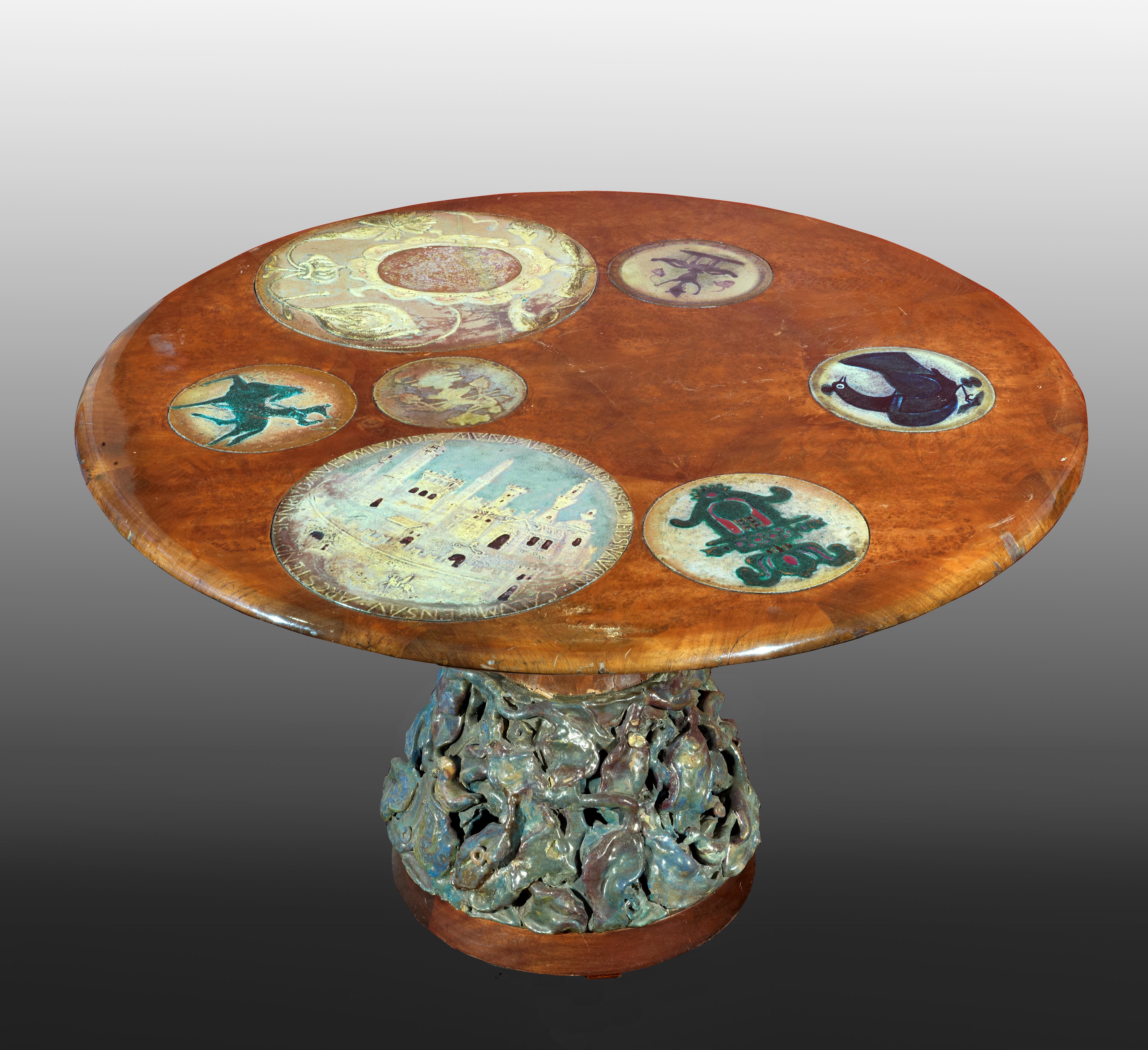 Coffee table around 1950s attributed to Pietro Melandri.
Ceramic and wood.
Amboina wood (loupe d’amboine) Height 62 cm, diameter 100 cm.
The top is decorated by 7 enameled ceramic plates. The plate decorated by a horse and the one decorated with
