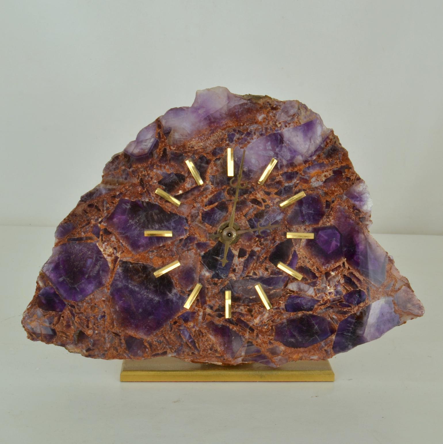 The Mid-Century Modern table clock is made of semi precious polished sliced quartz stone with amethyst insertions. The face with 12 hour brass markings mounted on a brushed brass base runs perfectly with AA battery operated quartz movement.