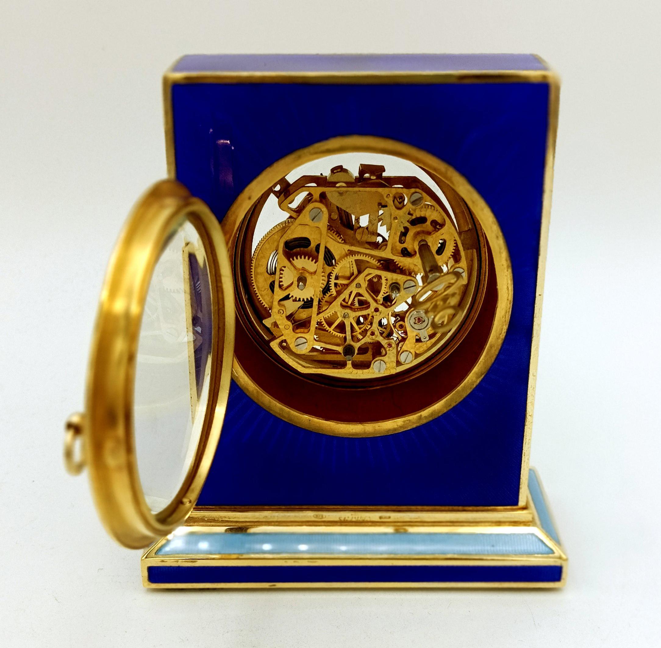  Tischuhr aus 925/1000 Sterlingsilber, vergoldet mit durchscheinendem Feueremail auf Guillochierung und feinen Handgravuren. Die Uhr hat eine Basis von cm. 4 x 10 und ist rechteckig cm. 8 x 10,2 x 2,3 Gesamthöhe cm. 11.5. Silber Gewicht gr. 498.